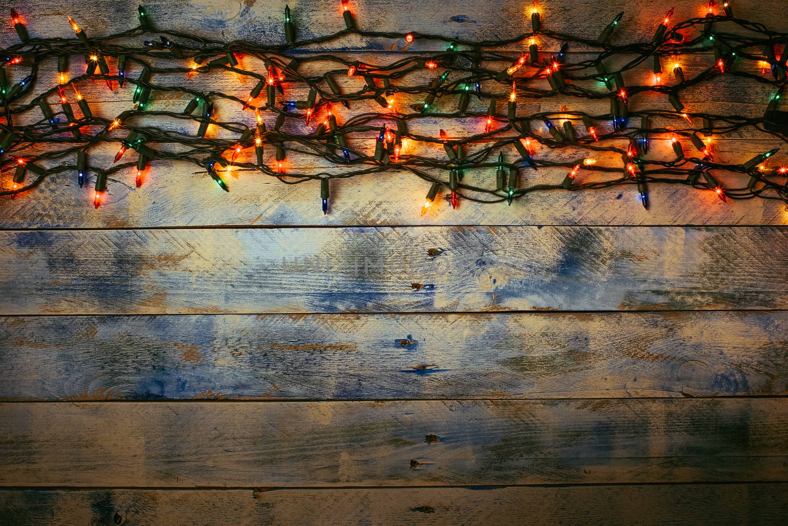 Christmas lights over white and blue painted planks for background. Christmas light decorations on wood texture. Flat lay, top view, copy space. Garland.