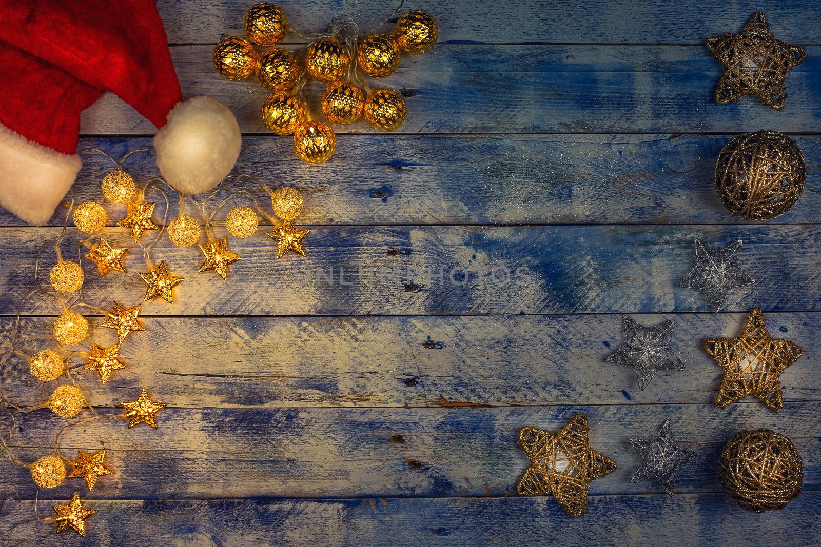 Christmas background with santa hat and christmas lights on rustic vintage wooden background. Garland. Flat lay, top view, copy space. Horizontal shot.