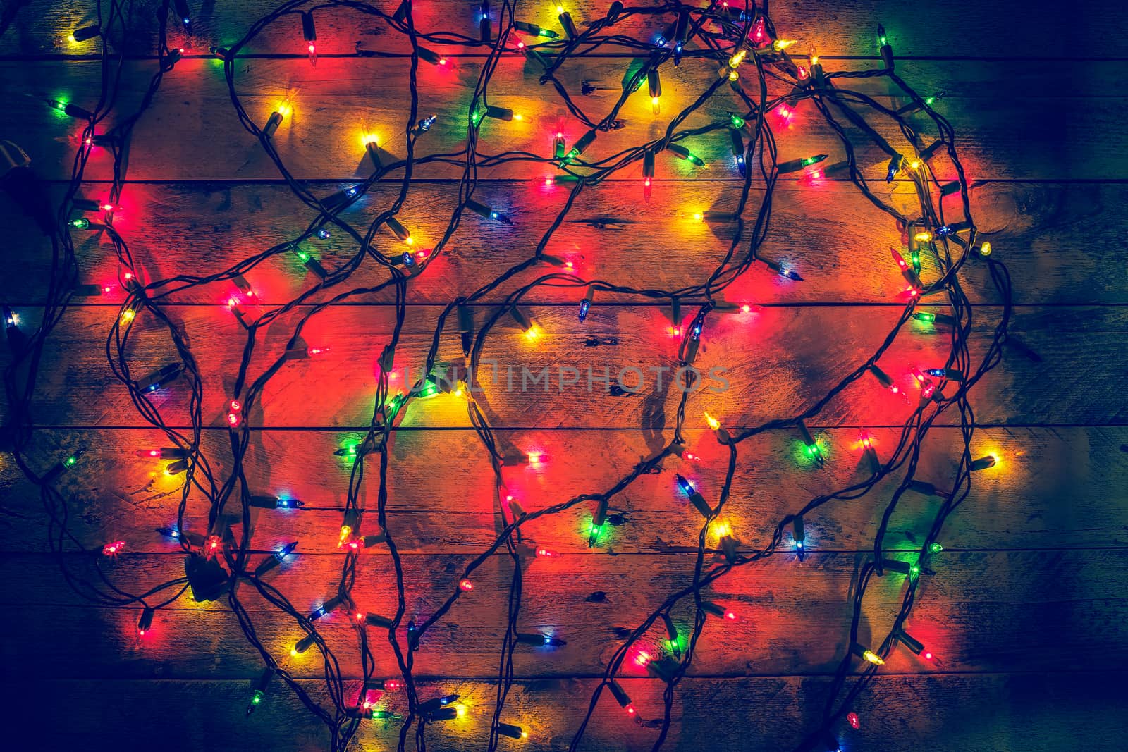Glowing colorful Christmas lights on a wooden background. Christ by BarisevRoman