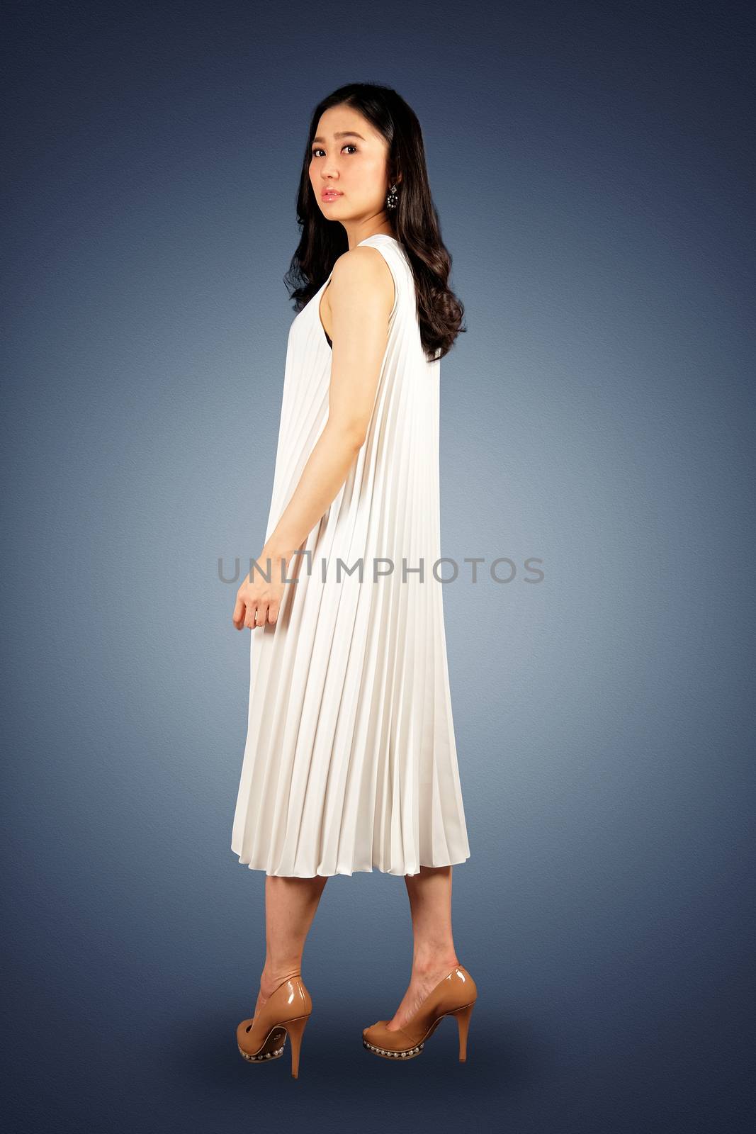 Young asian woman in white dress looking at the camera on dark blue background with clipping path