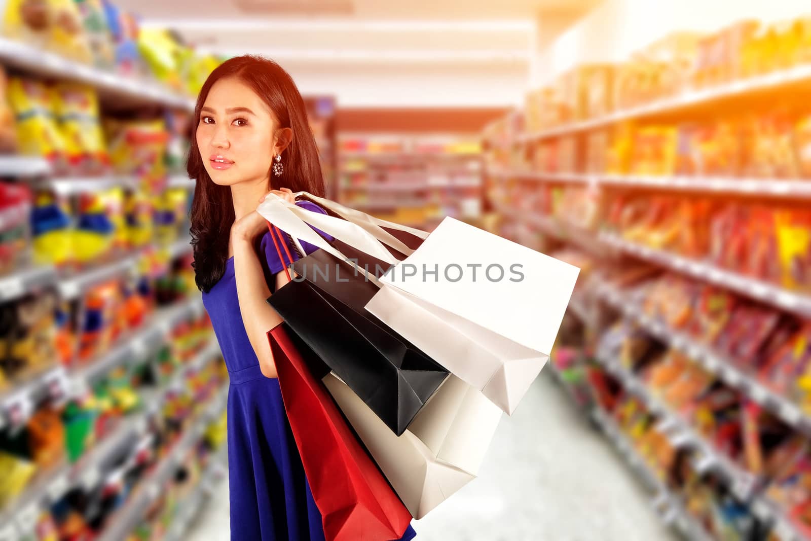 Happy women in blue dress with a shopping bag in shopping mall