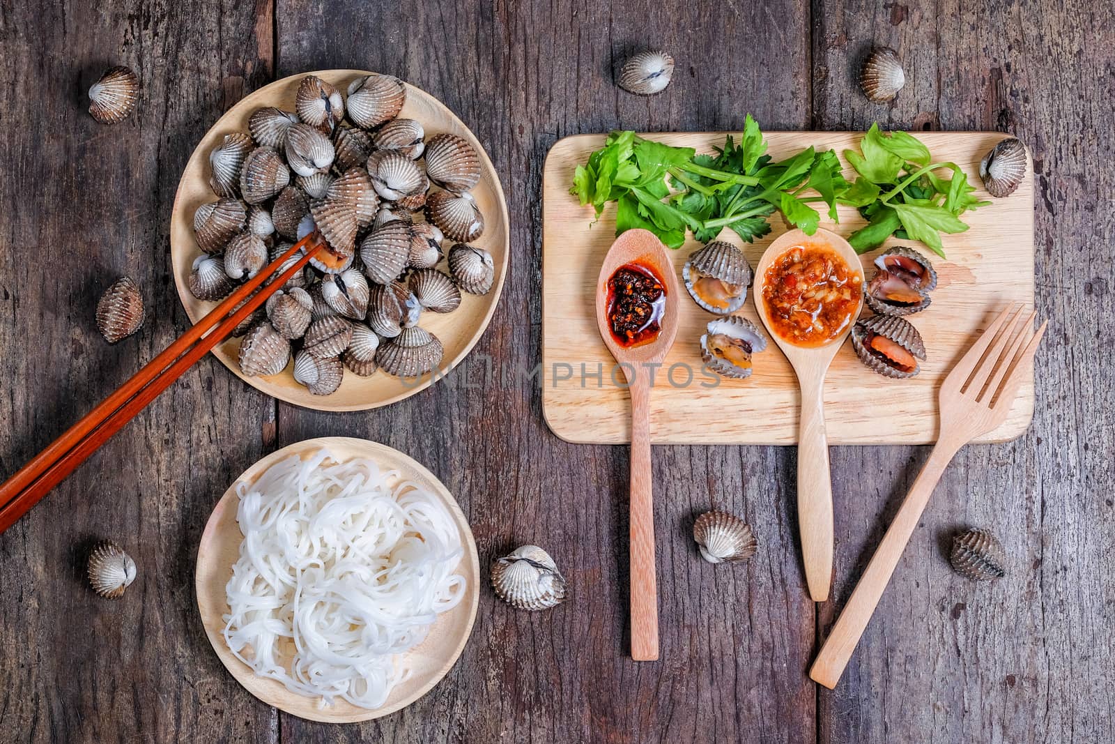 Boiled cockles with tasty seafood sauce on wood background