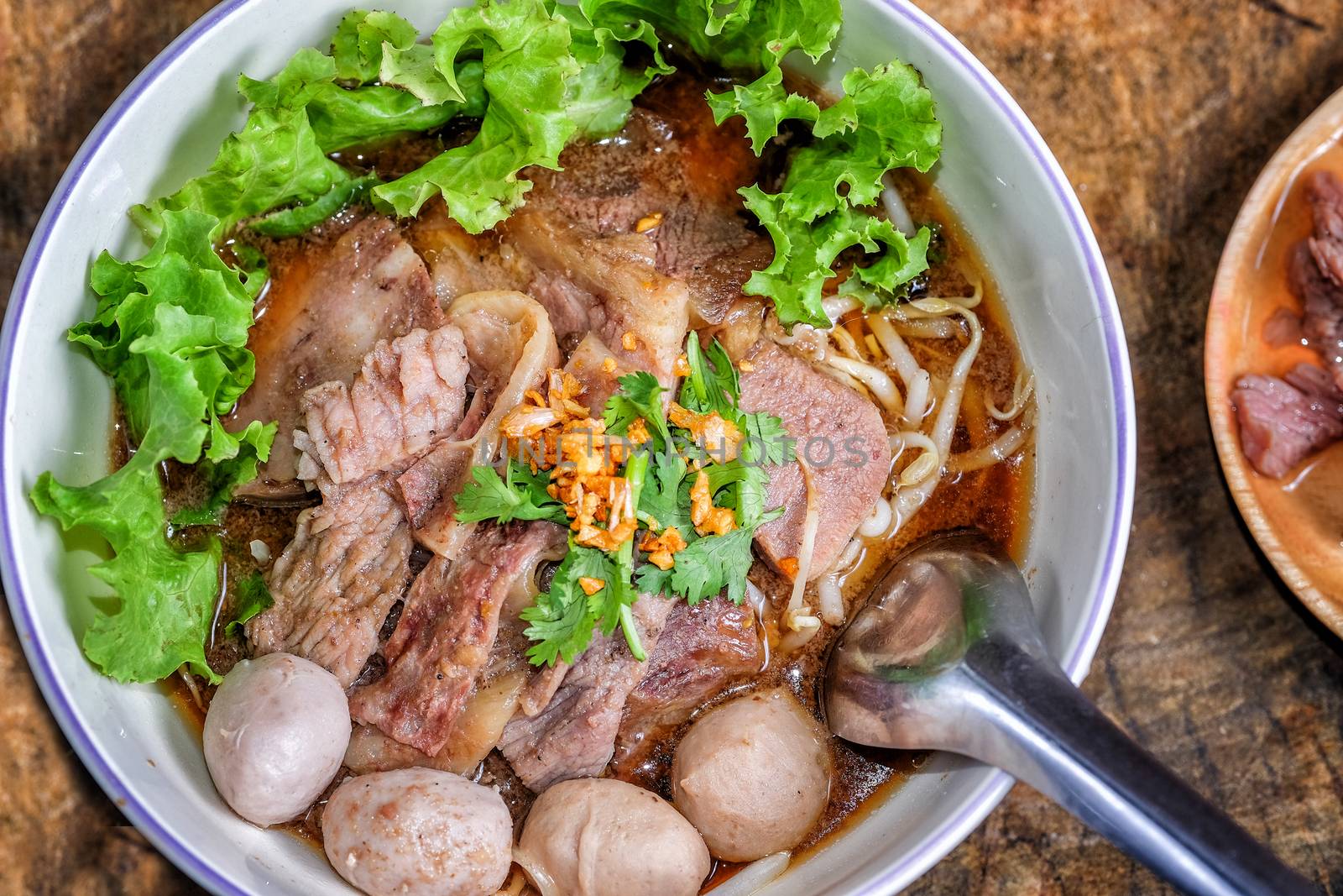 Thai food Noodle soup with beef on wood background by Surasak