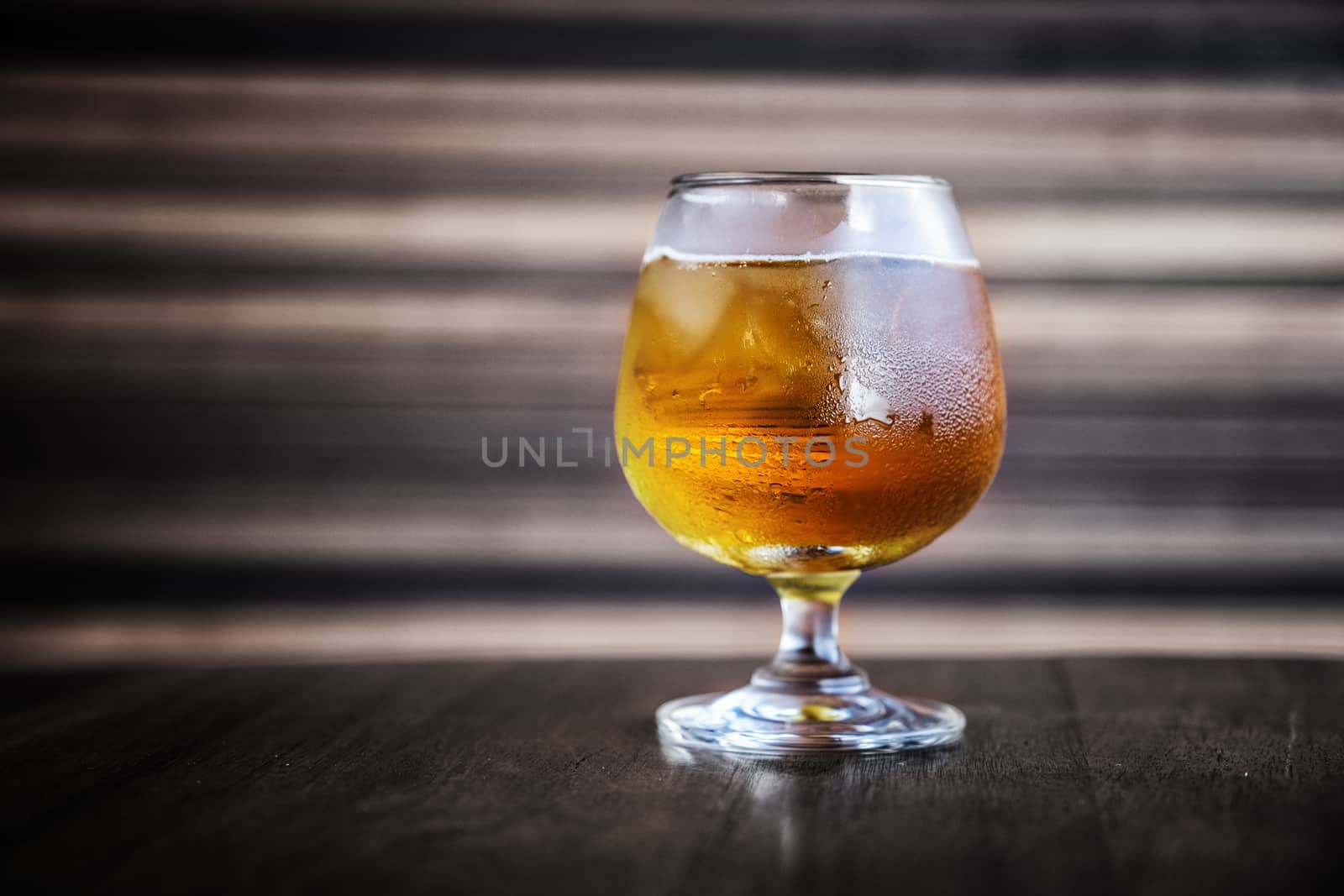 Glass of light beer on a dark room by Surasak