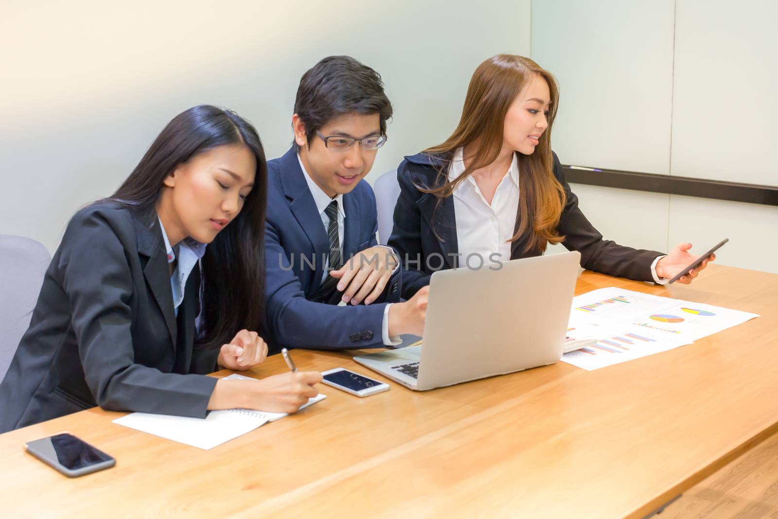 Asian business people make a group discussion in meeting room with document and computer putting on wooden table