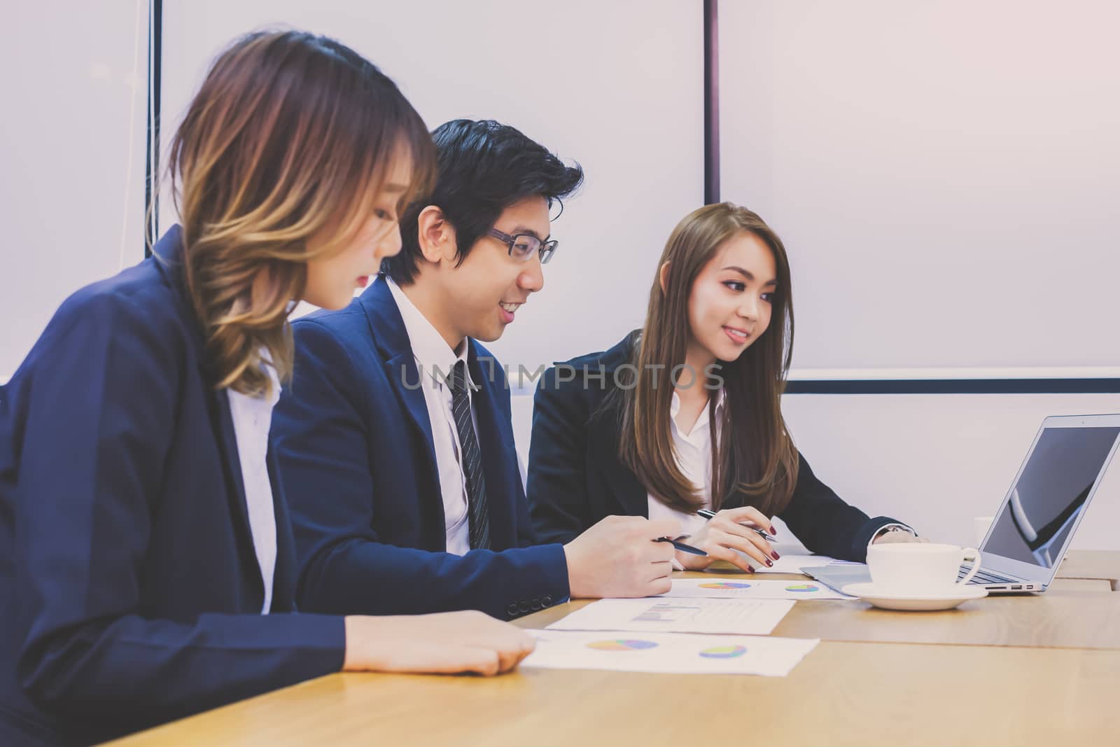 Asian business people make a group discussion in meeting room with document and computer putting on wooden table