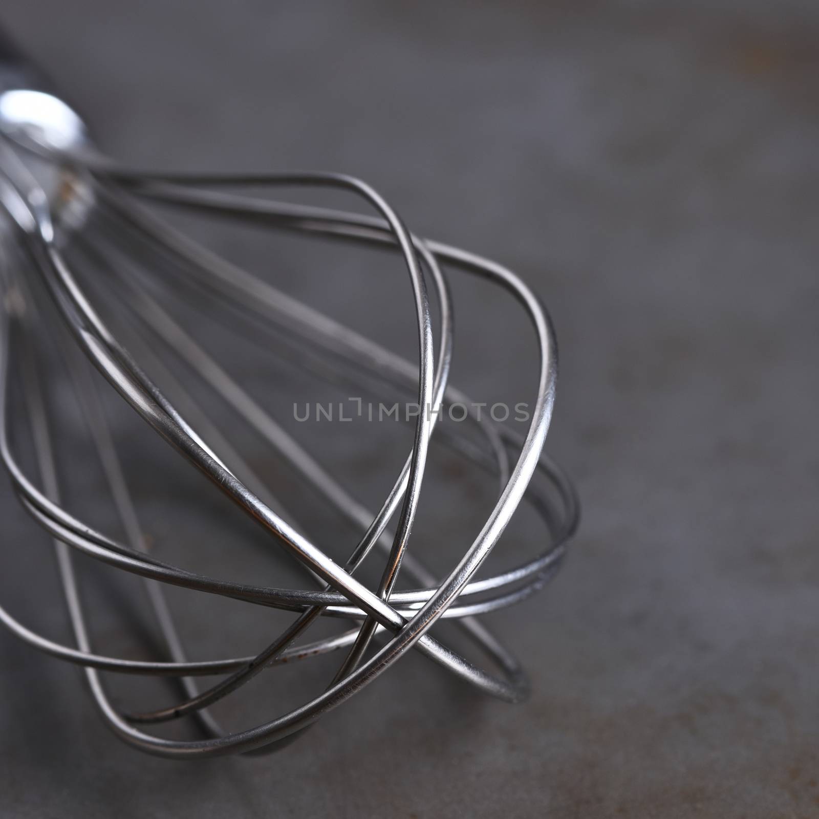 Closeup of a kitchen whisk on a metal surface, with shallow depth of field.