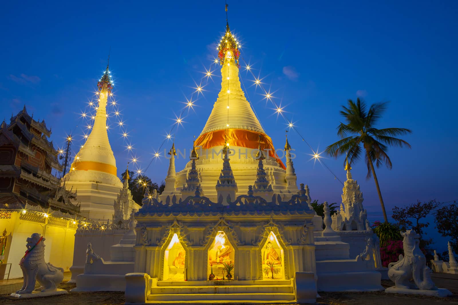 A white color of pagoda decorated by lighting at night time under clear sky located at north of Thailand