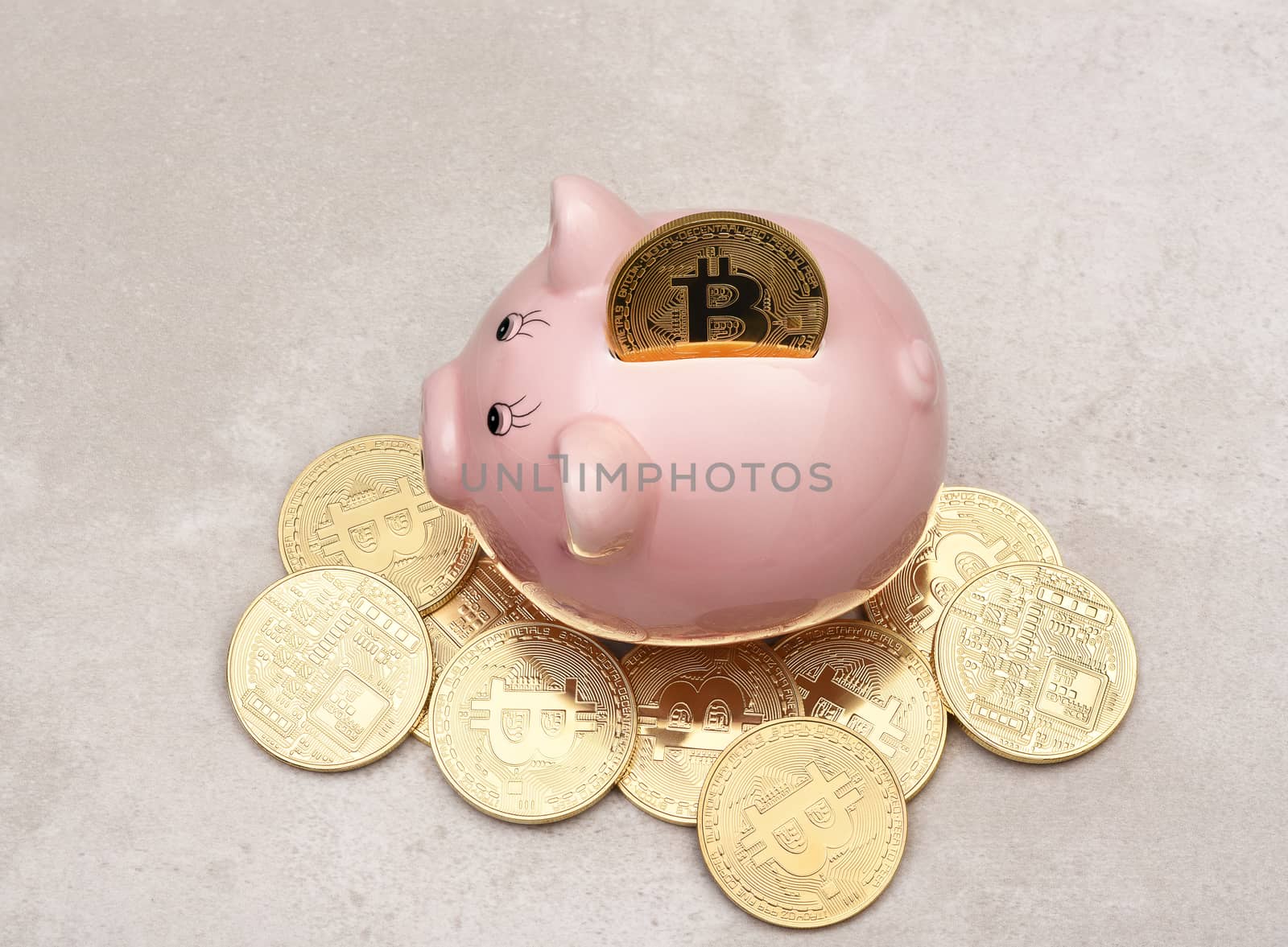 Savings Concept: A Bit Coin in the slot of a piggy bank with more coins on the table.