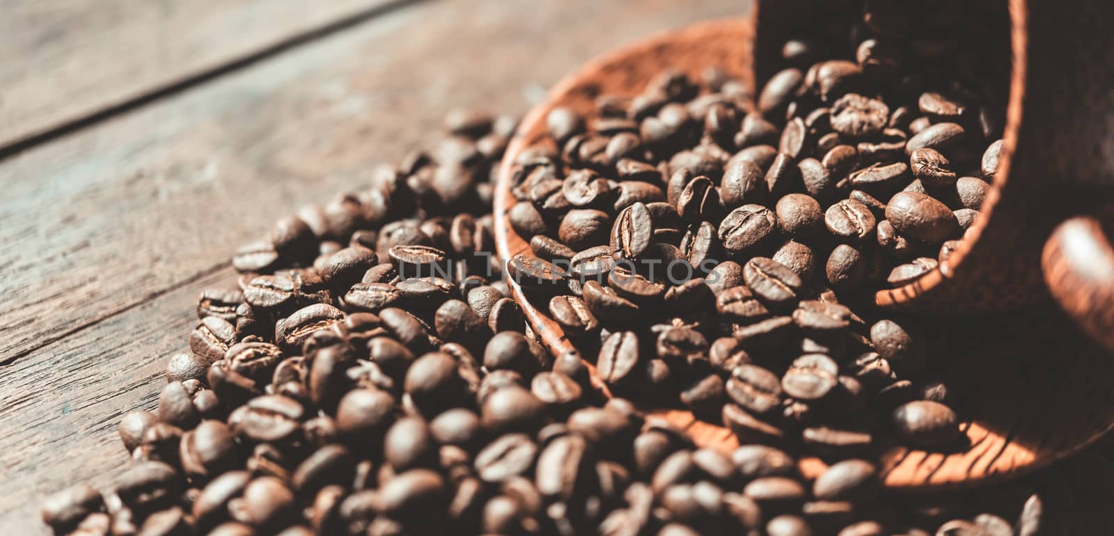 Roasted coffee beans in wood cup on wooden background