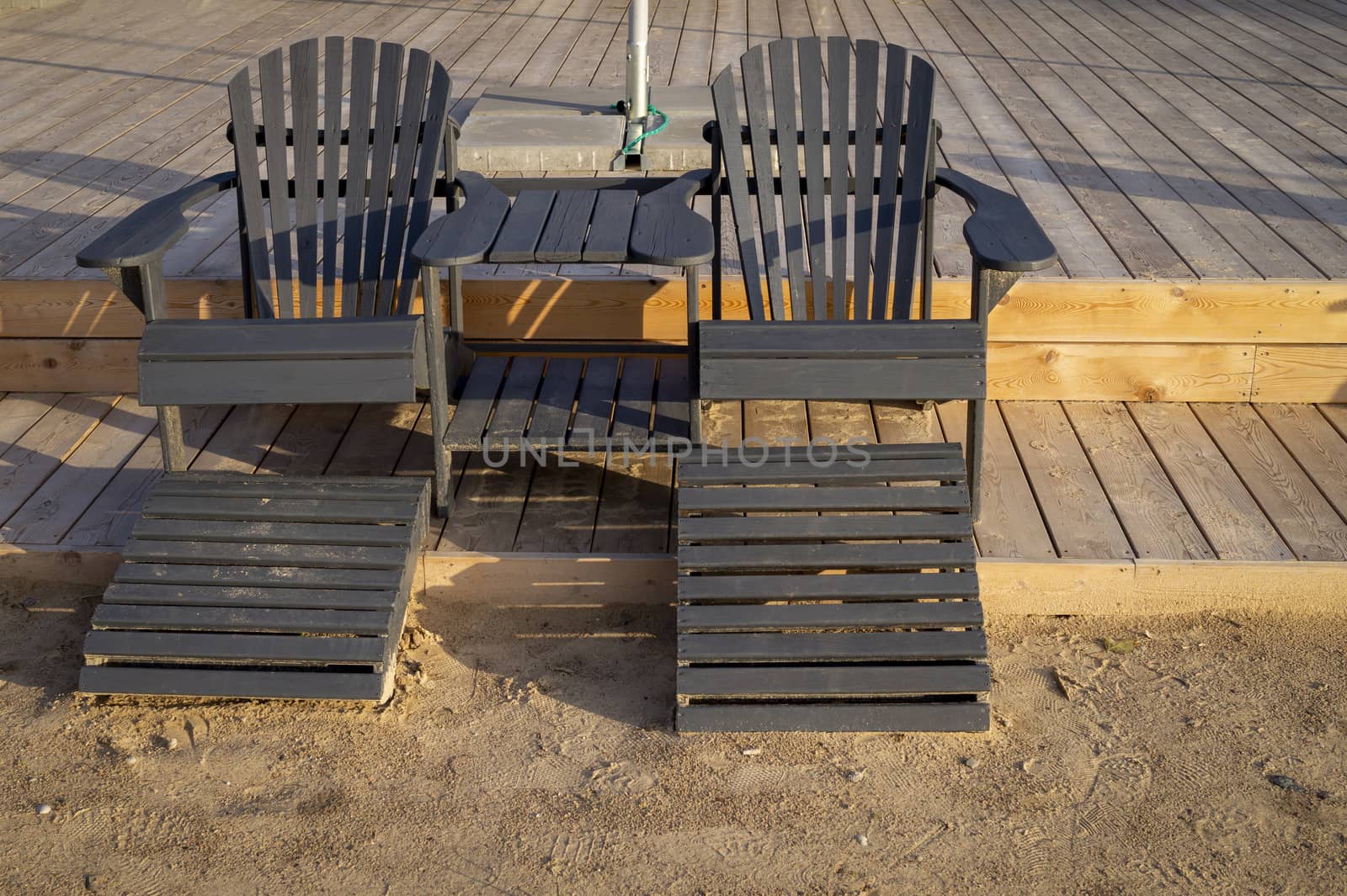 Empty wooden beach chairs at the edge of a deck by NetPix
