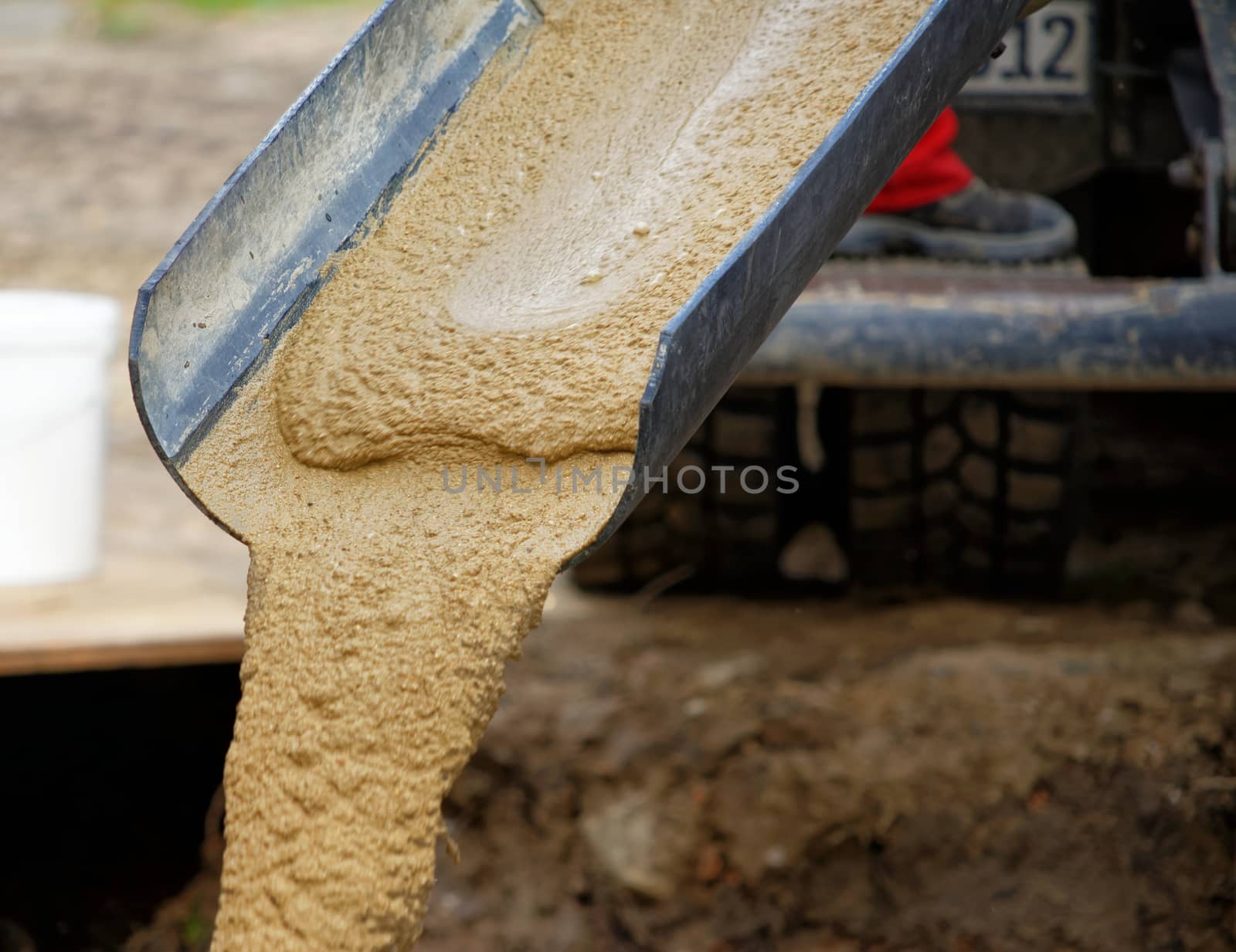 Liquid soil is poured from the ramp of concrete mixer by geogif