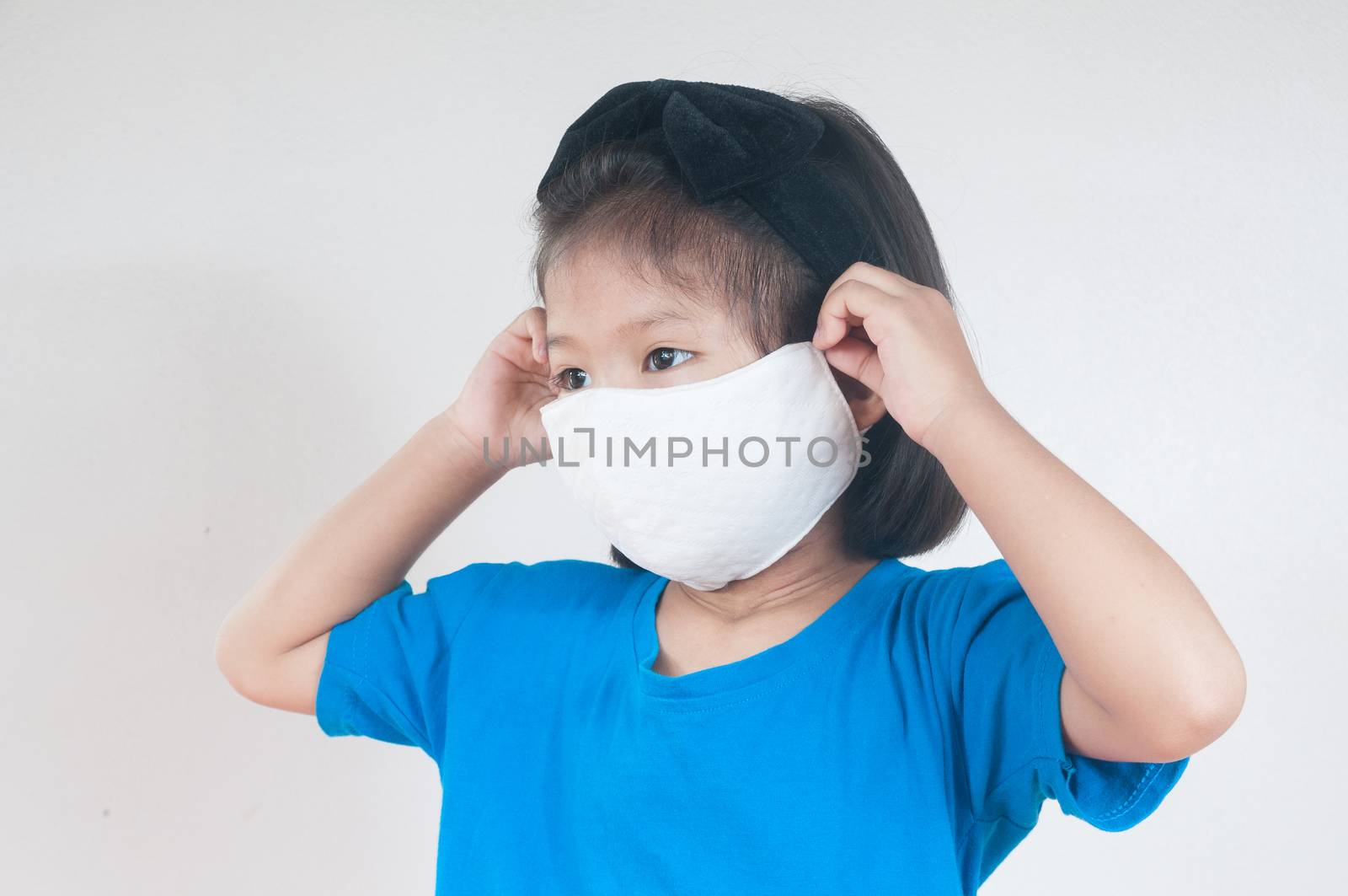 Asian child Girl or kids in blue Shirt wearing cloth mask to protect Covid 19 virus infection as medical safety prevention concept against white background.