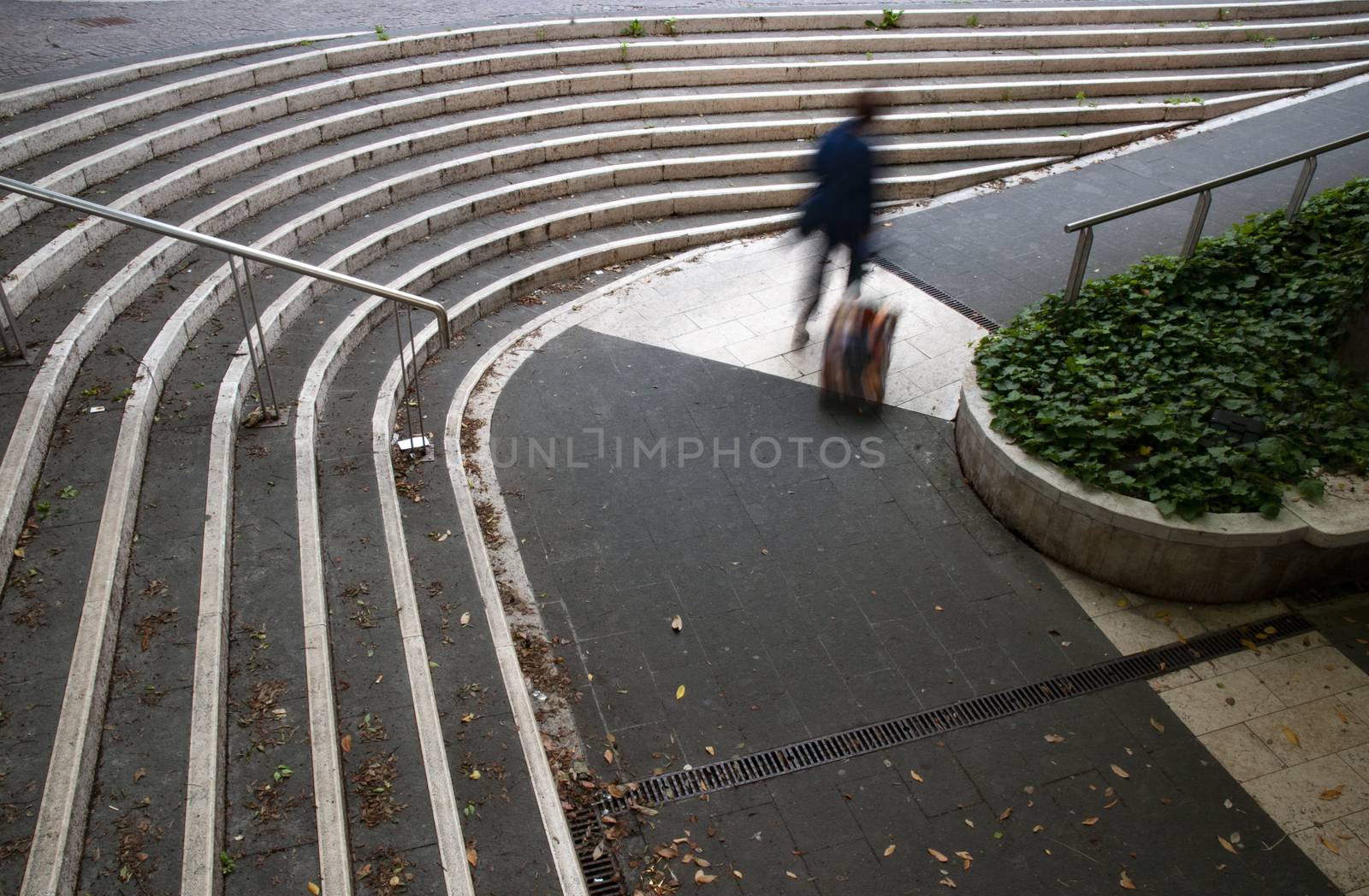 A blurred woman walking with luggage outside of railway station