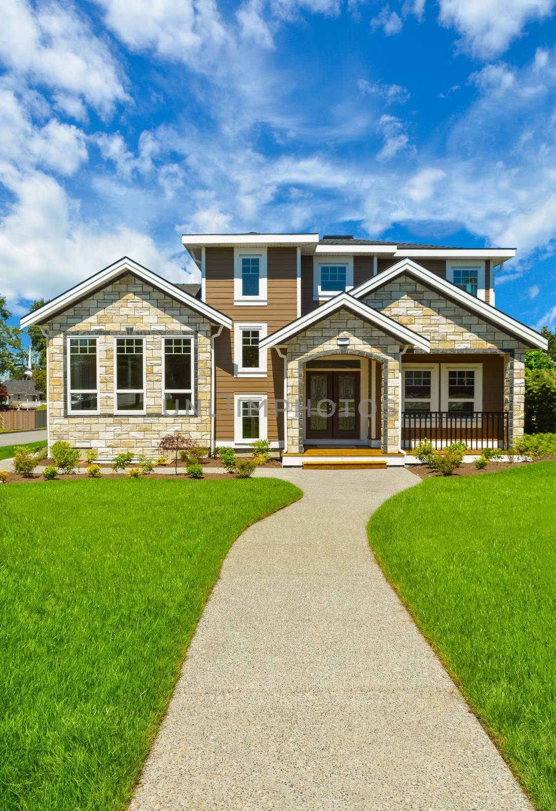 Pathway to Ideal residential house in perfect neighbourhood. Brand new family house with big green lawn in front on blue sky background