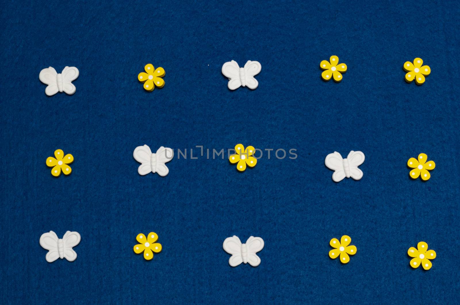 White wooden butterflies in formation with yellow flowers as background resource
