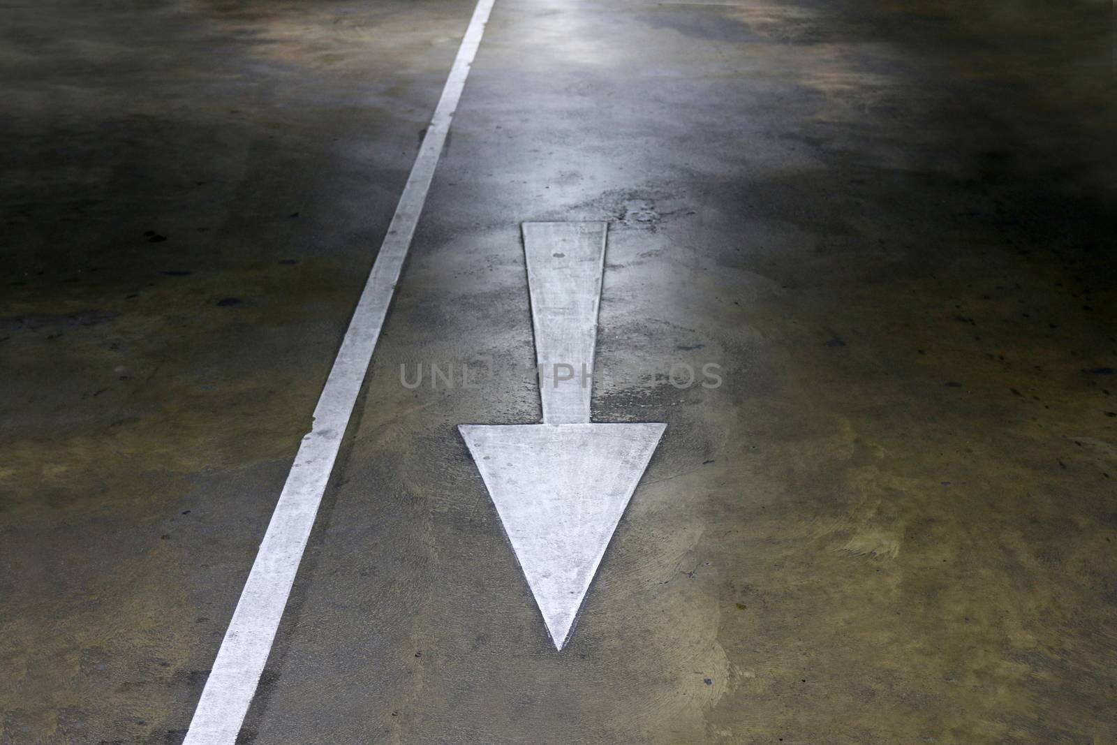 white arrow symbol sign on cement floor walkway parking
