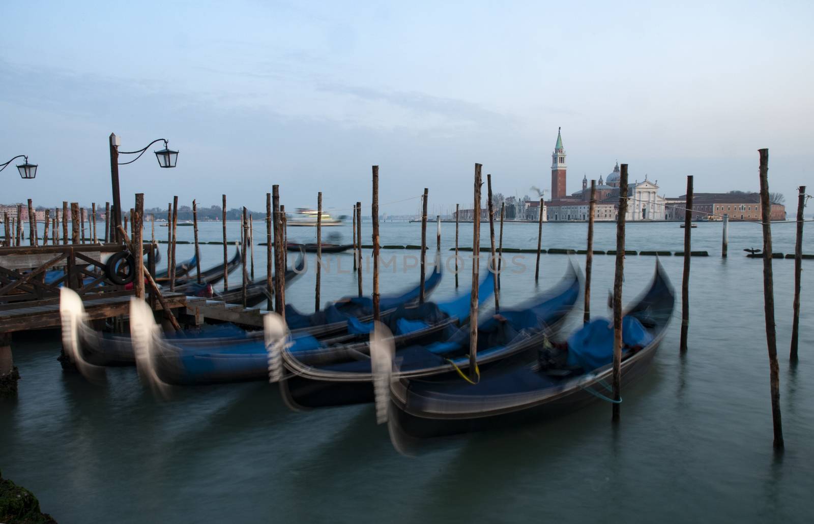 Blurred gondolas in the gondola parking area in front of St. Mark square with St. Clemente island in background
