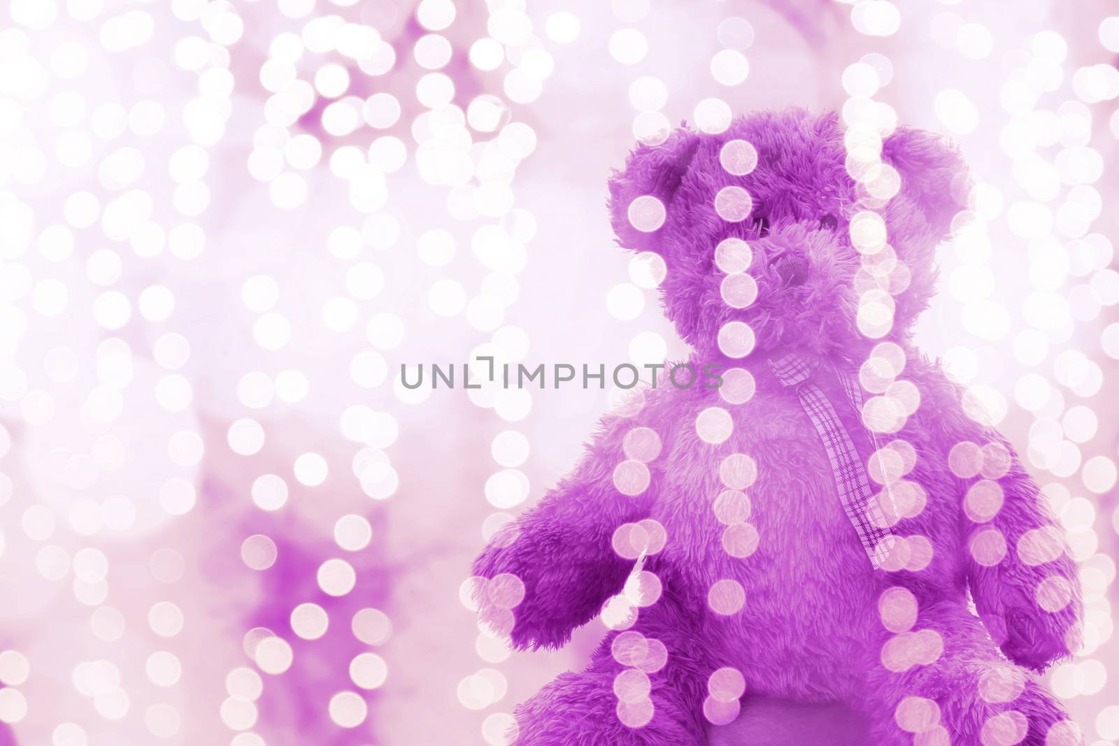 Teddy bear doll in Lighting line bokeh purple bright for Christmas or happy new year Background, Bear Sitting lonely in glitter purple white background Blurred bokeh bright (Selective Focus)