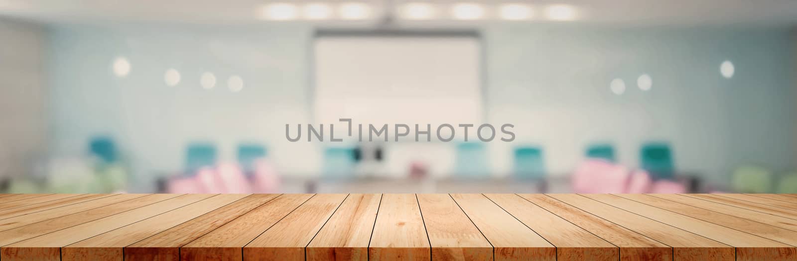 Panoramic empty clean wood counter table top on blur student study in classroom white light background for product education learning hall centre, Abstract Blurry wooden desk scene display or montage.