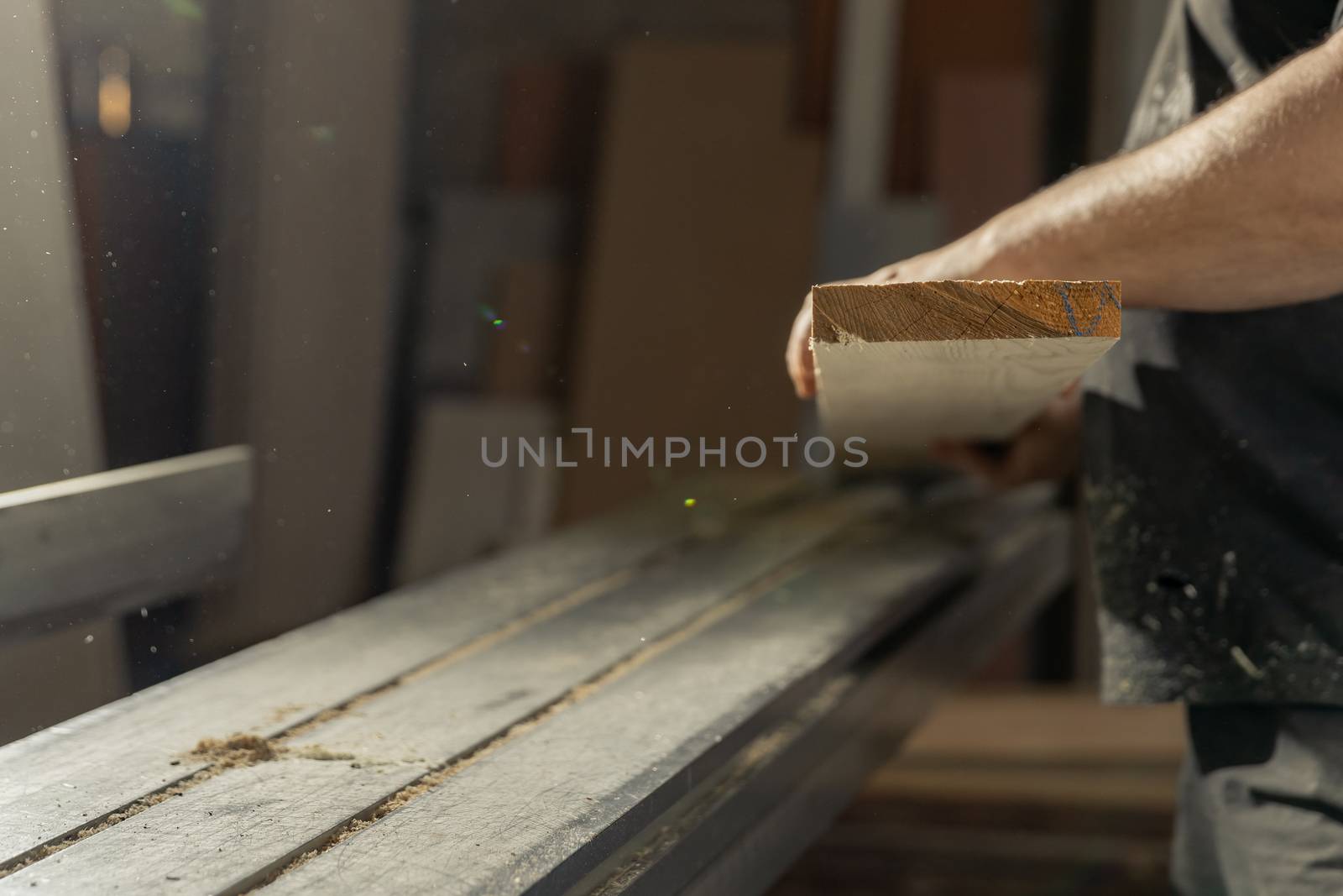 A man cuts wood on a circular saw in a joinery.