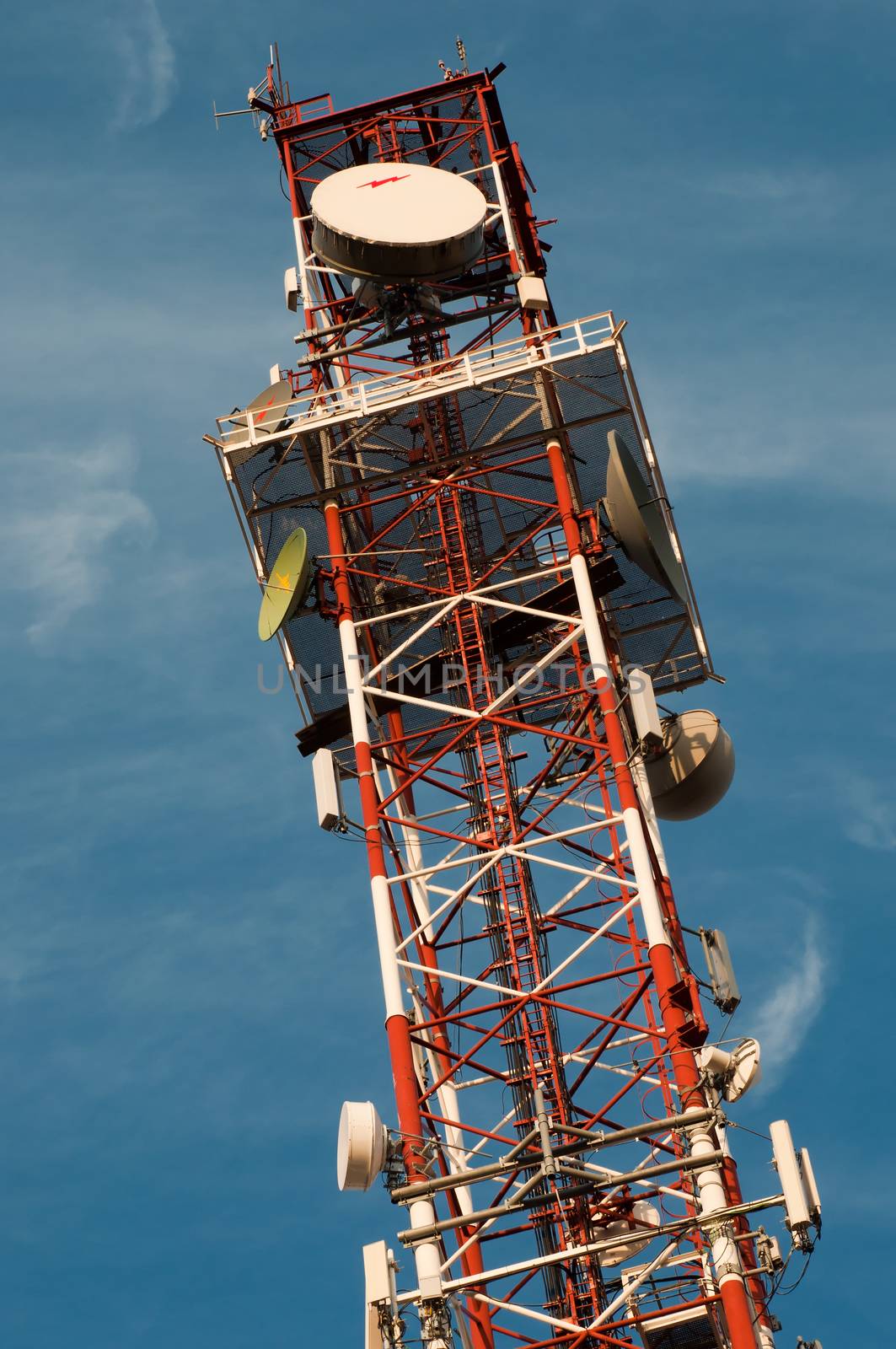 Red and white communication tower over a blue sky 