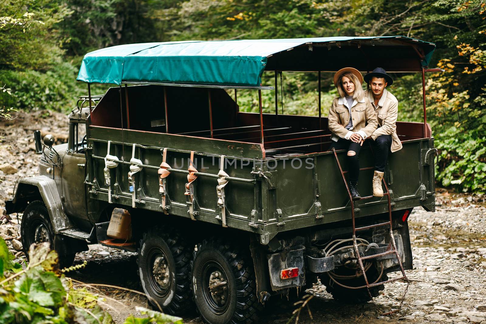 A beautiful girl and a handsome man in military truck. Lovestory. Military vehicle. Military fashion.Carpathian mountains by Denys_N