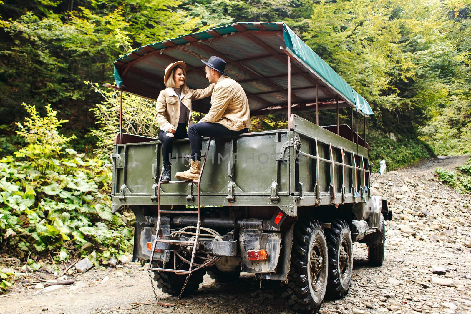 A beautiful girl and a handsome man in military truck. Lovestory. Military vehicle. Military fashion.Carpathian mountains.