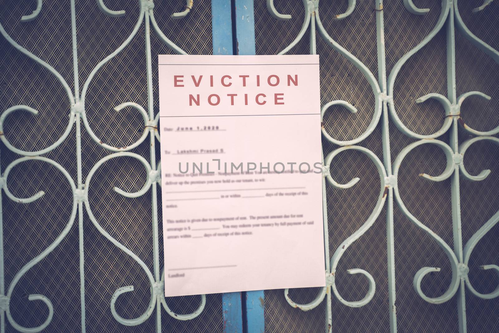 Foreclosed or eviciton notice on a main door with blurred details of a house with vintage filter. by lakshmiprasad.maski@gmai.com