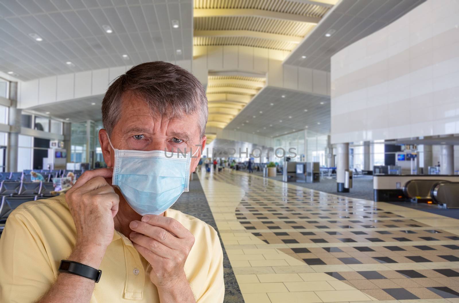 Senior man or traveler adjusting face mask in airport terminal and looking afraid of travel with coronavirus