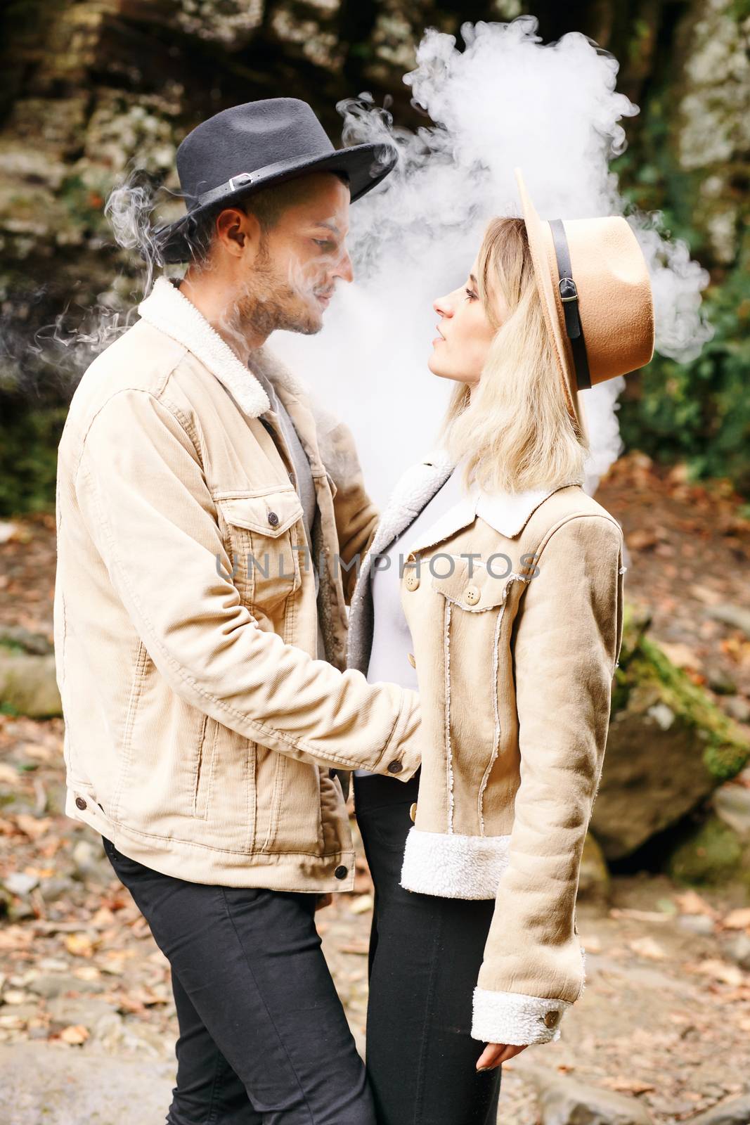 Couple in vape cloud. Two in smoke. Tourists in cold autumn forest with vape. Man and women in smoke. Two smokers. Beautiful couple in fog. E-cigarettes and people