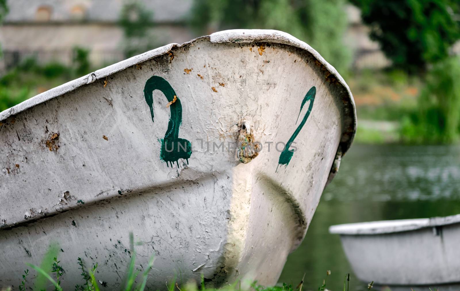 old boat number two on the river bank on green grass without people