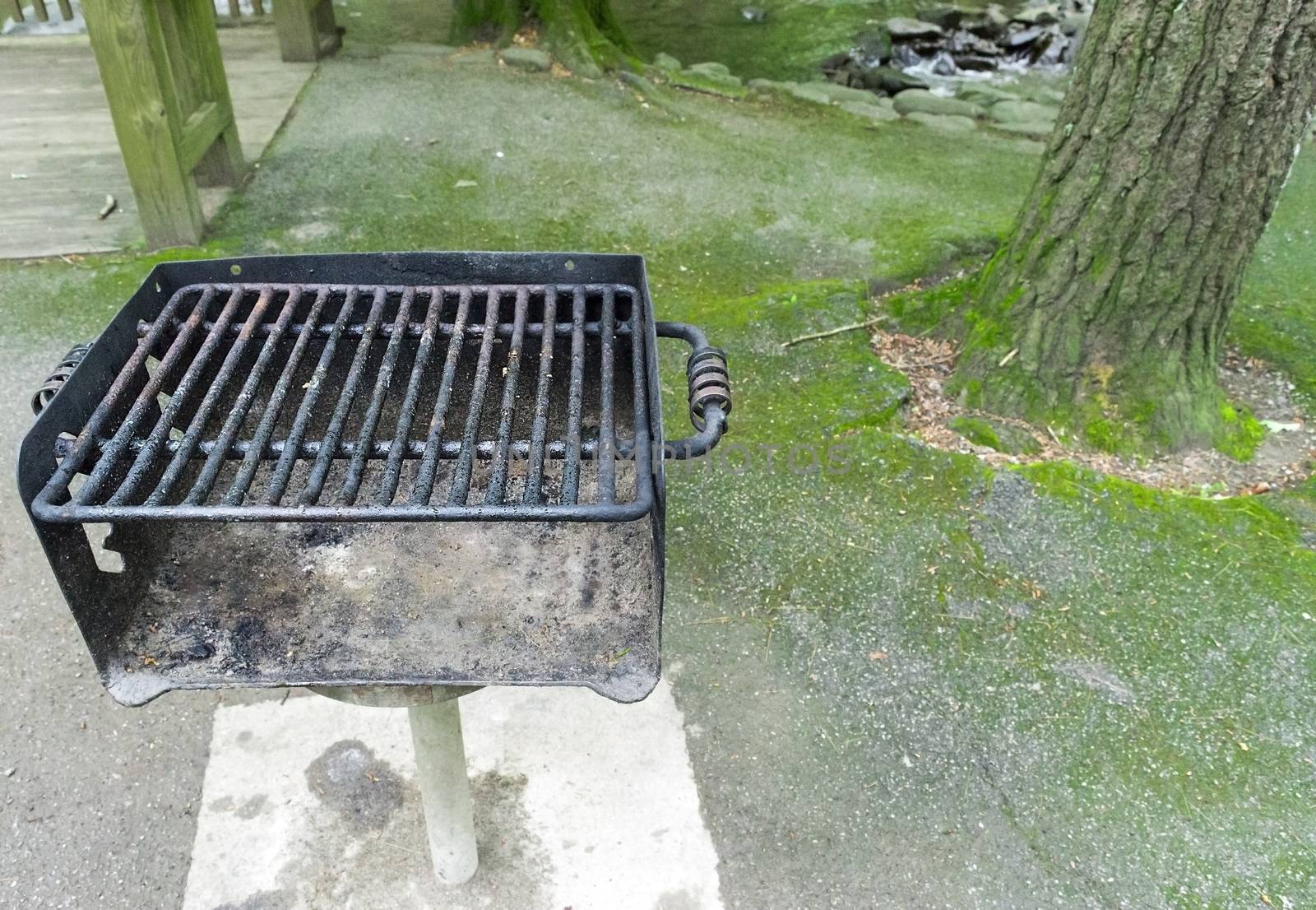 Horizontal shot of a used pubic area barbecue grill in a picnic area with copy space.