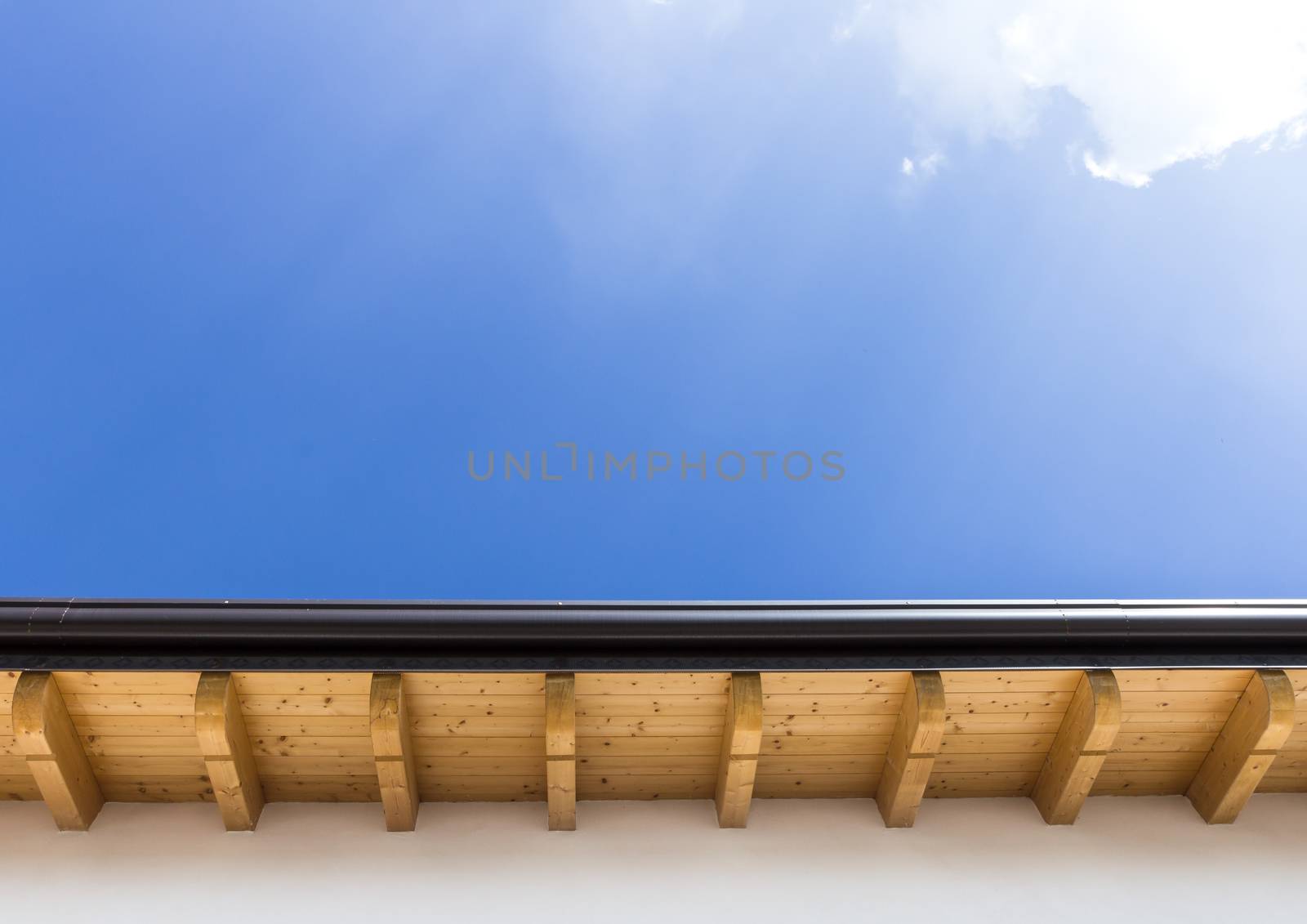 Low angle view of new house with wooden roof and gutter against clear blue sky