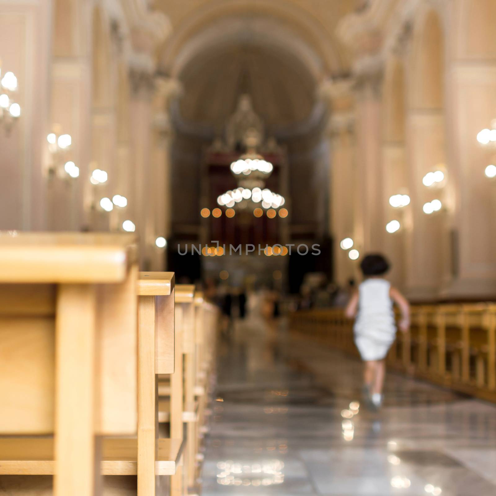 A little girl runs to church, heading for the altar. Defocused blurry background.