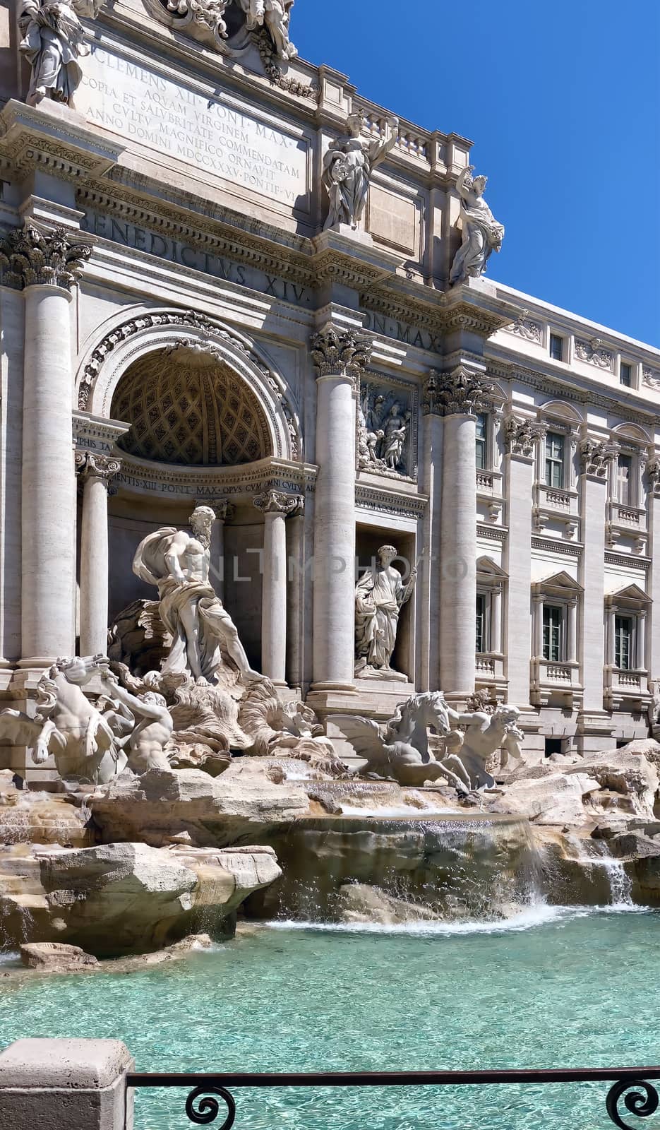 the facade of the Trevi Fountain in Rome, one of the main tourist attractions in Italy. Baroque architecture and sculpture. Historic building facade. Water flowing from the fountain. Sunny summer day