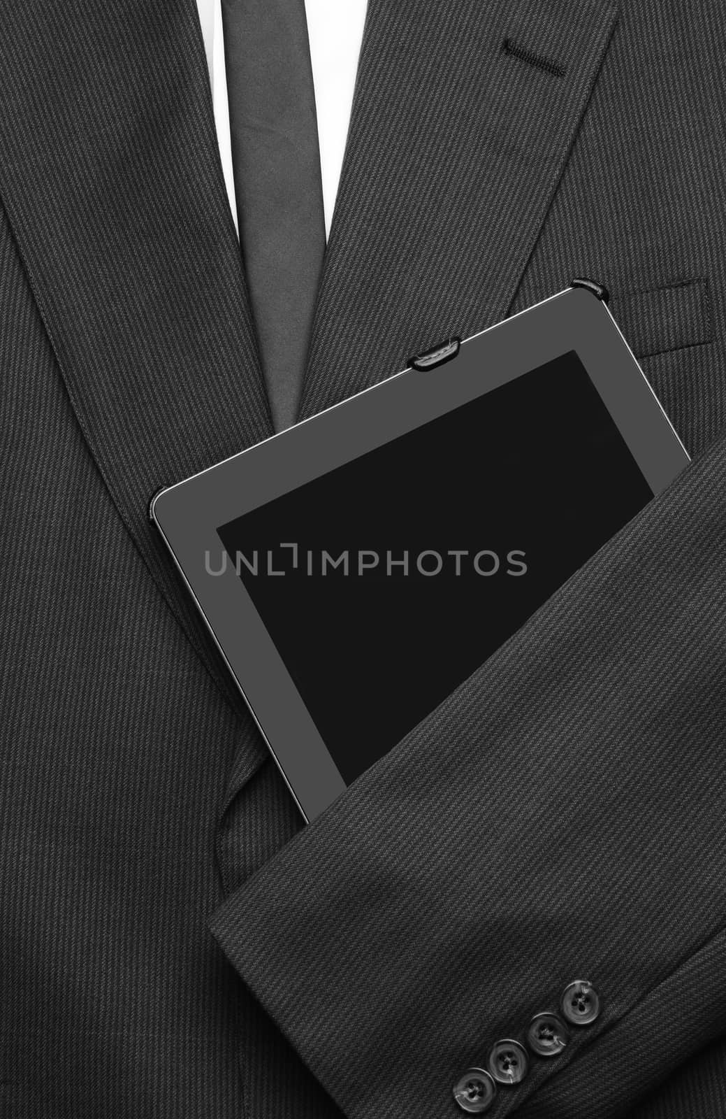 Closeup of a business jacket with white shirt and tie with one arm over a tablet computer. the empty suit is laid out and ready for the day. The screen is blank.