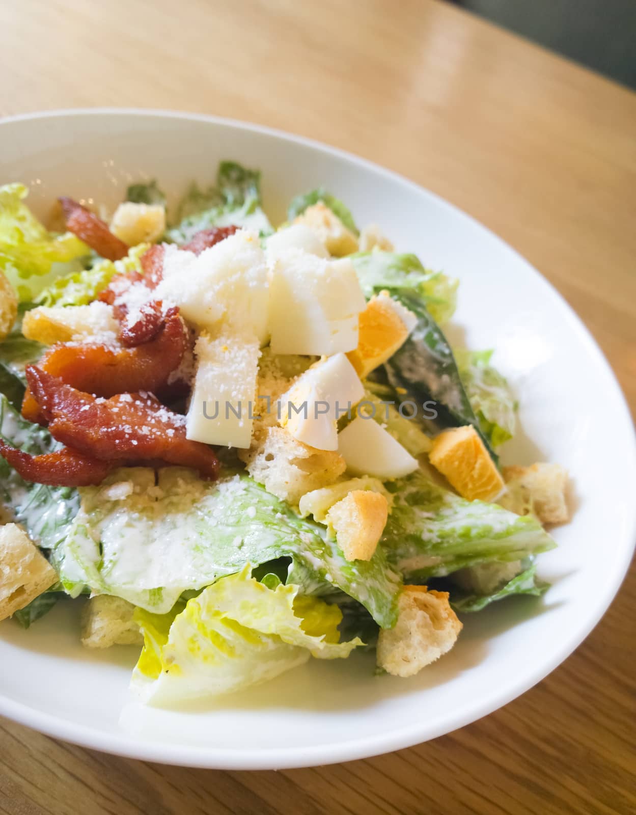  caesar salad placed on top of a wooden table by everythingpossible