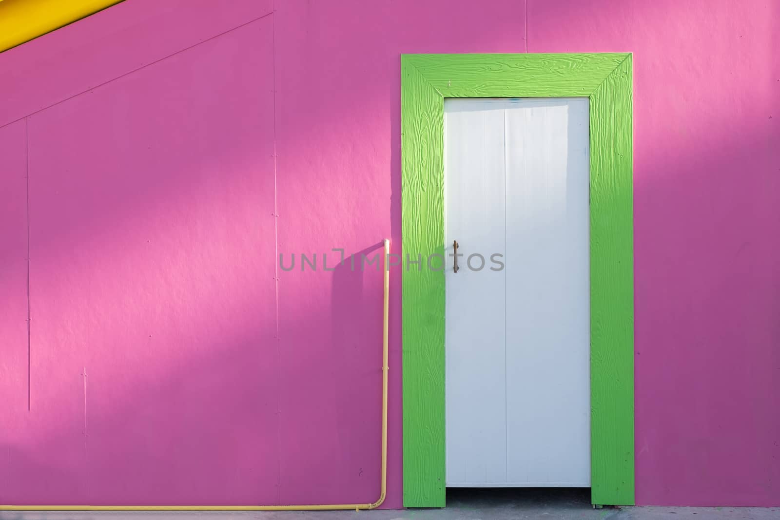 Green wooden doors and pink wall in sunlight by Surasak