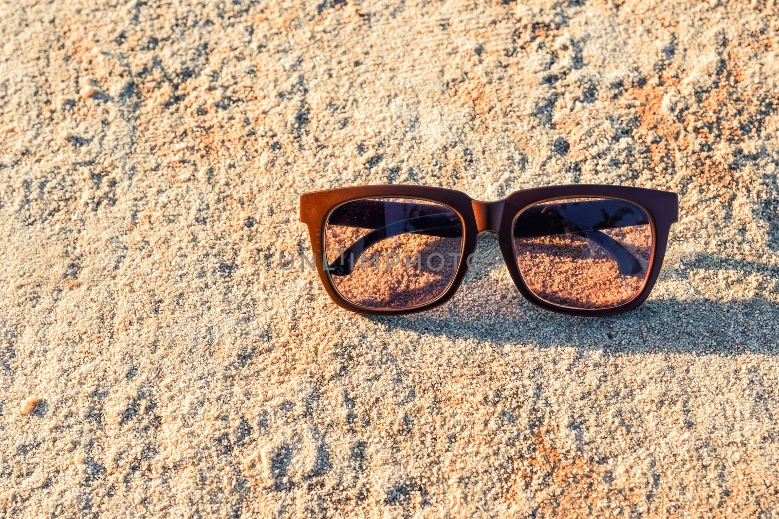 Black Sunglasses on the beach with color filter by Surasak