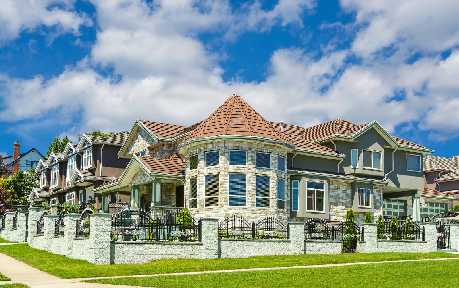 High end custom built luxury house with rotunda in a residential neighborhood on cloudy sky background