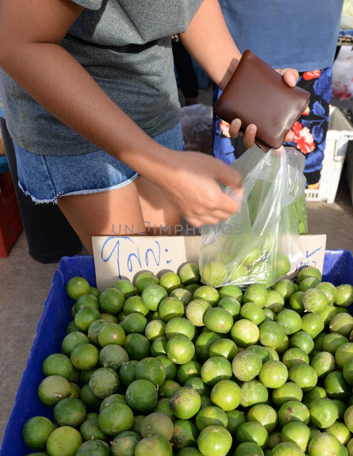 Housewives are choosing green lemons in the Thai market.