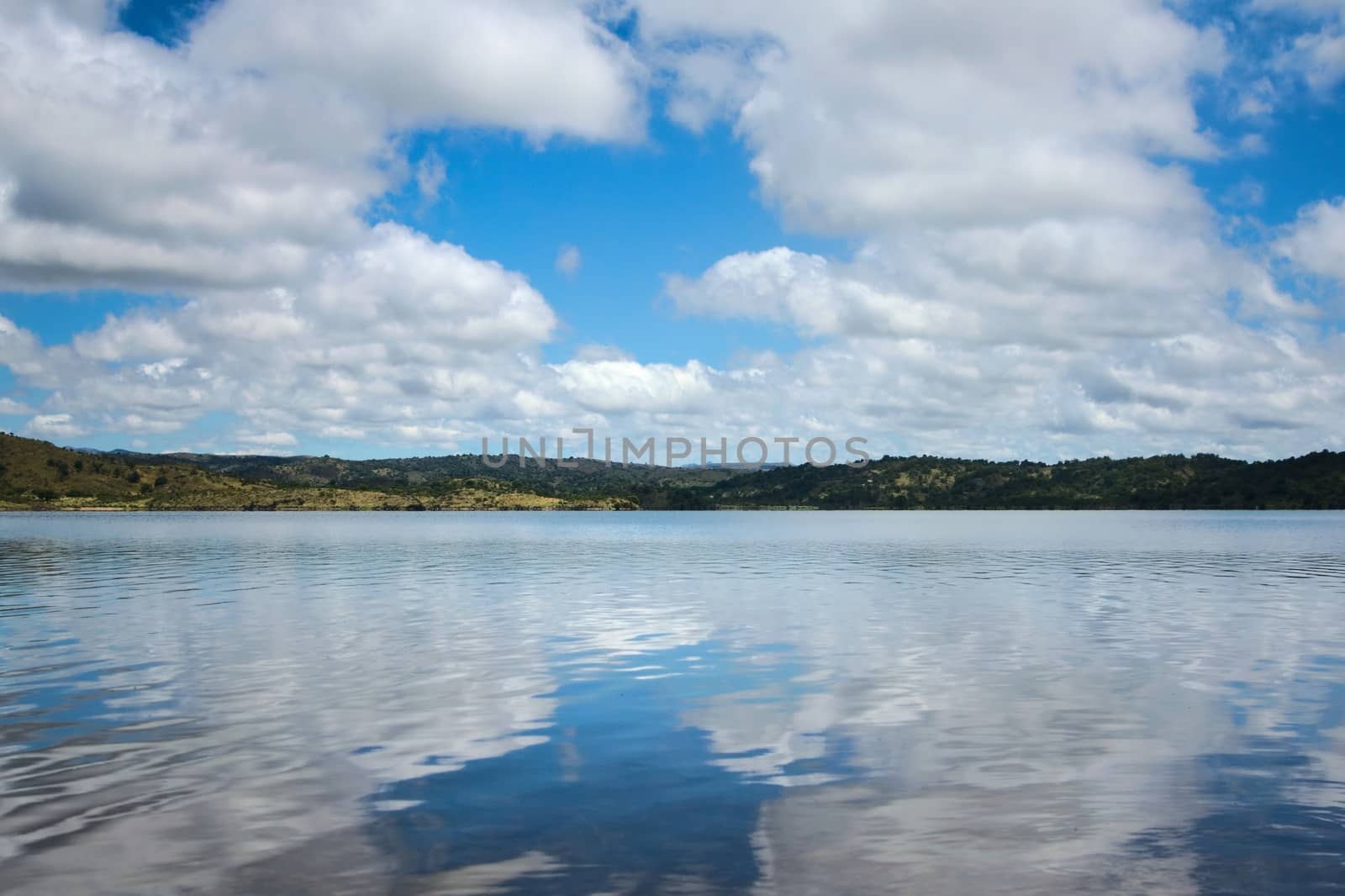 Cumulus clouds reflected on the waters of a lake by hernan_hyper