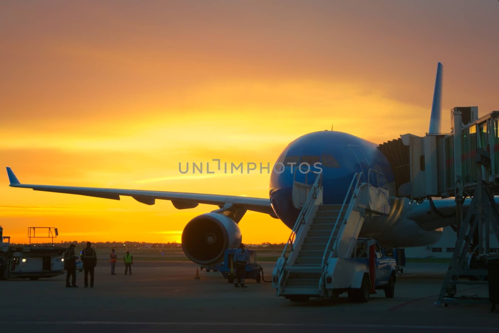 Airport ground crew loading cargo and luggage on a commercial aircraft at dawn. by hernan_hyper
