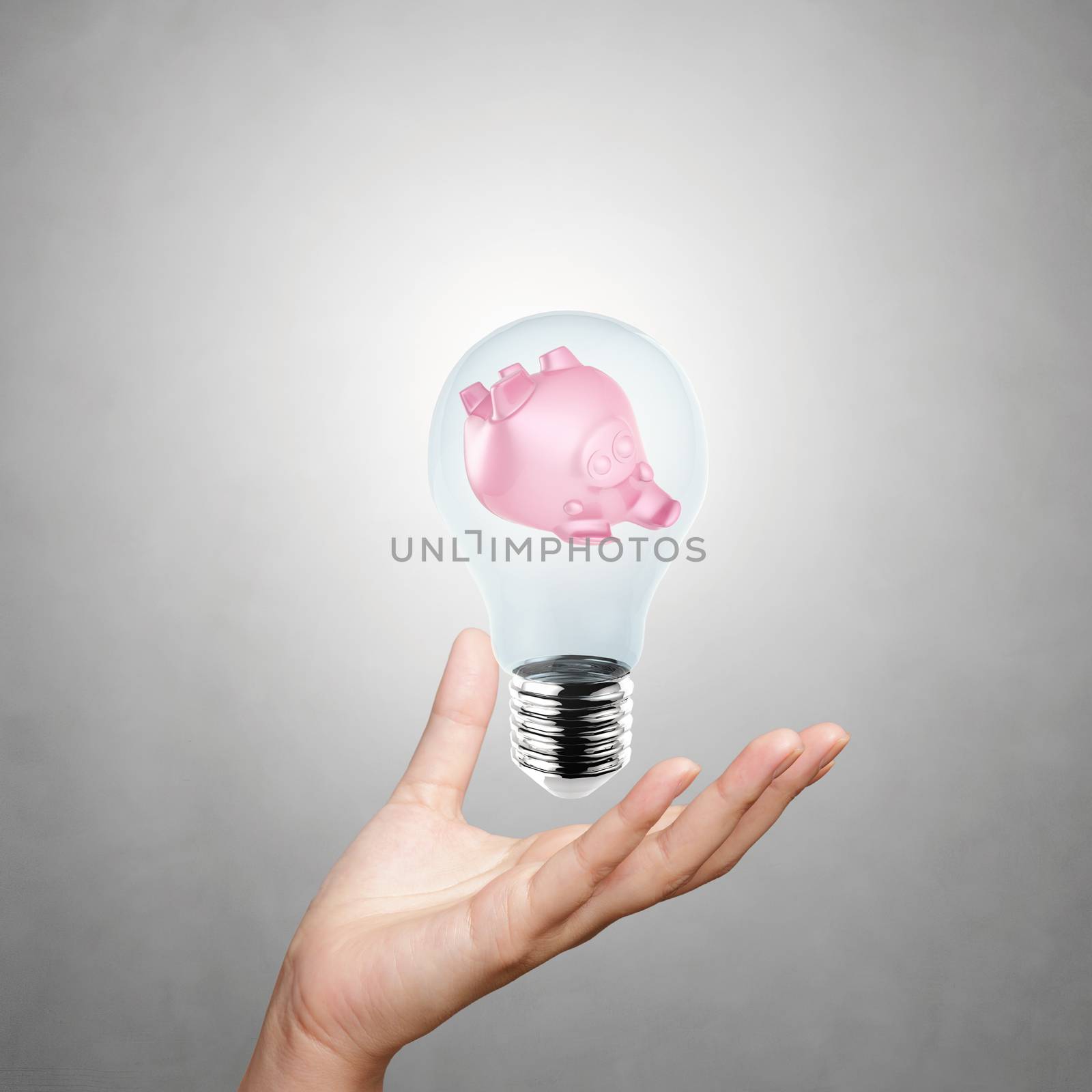 hand showing piggy bank with light bulb as concept
