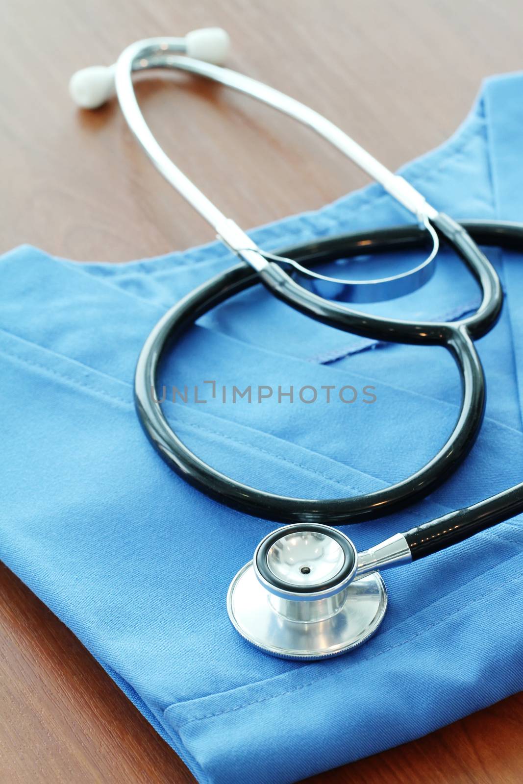 Stethoscope with blue doctor coat on wooden table and  background 