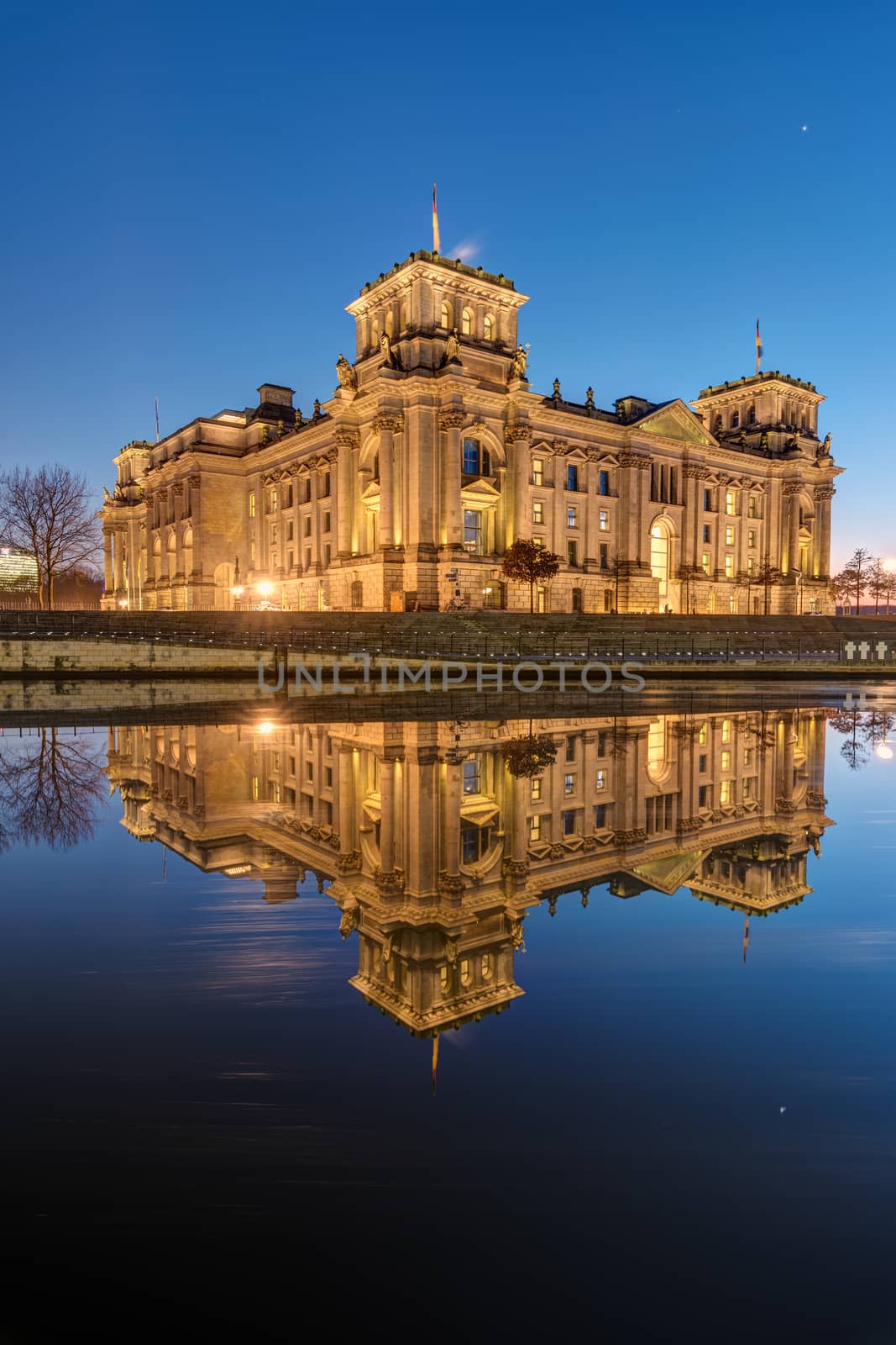 The famous Reichstag in Berlin at dawn reflects in the river Spree