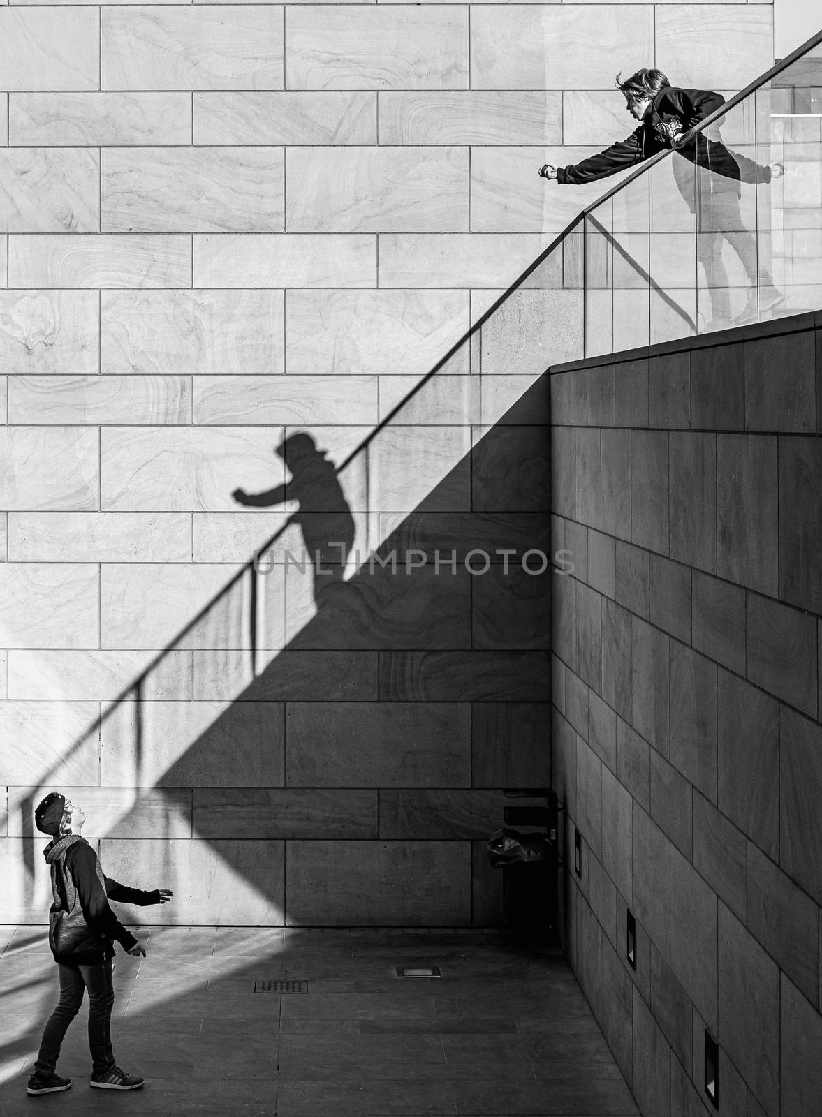 Black and white image of 2 young boys on different levels playing with a bouncy rubber ball