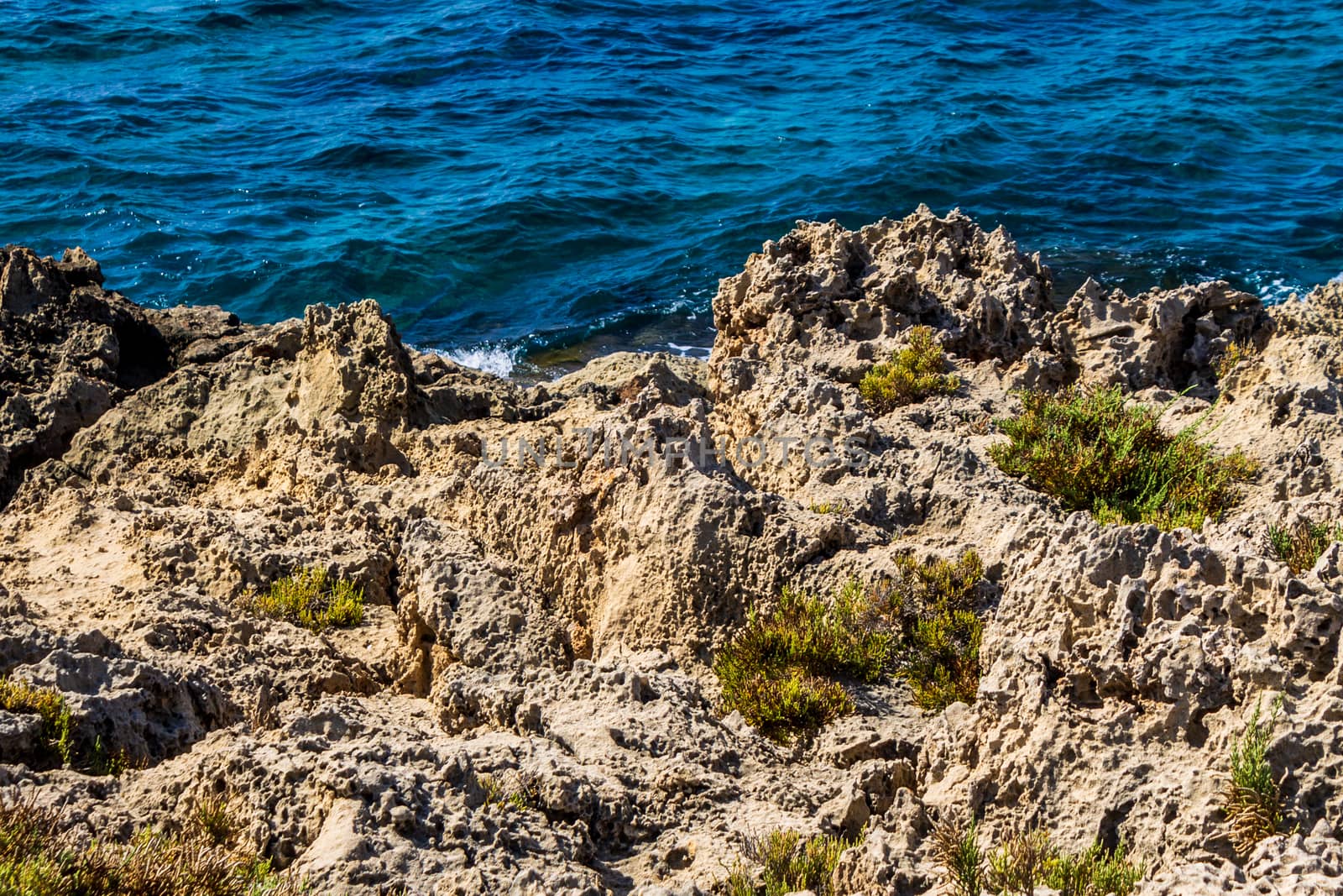 Mediterranean coast on a sunny day with rocks and blue waves.