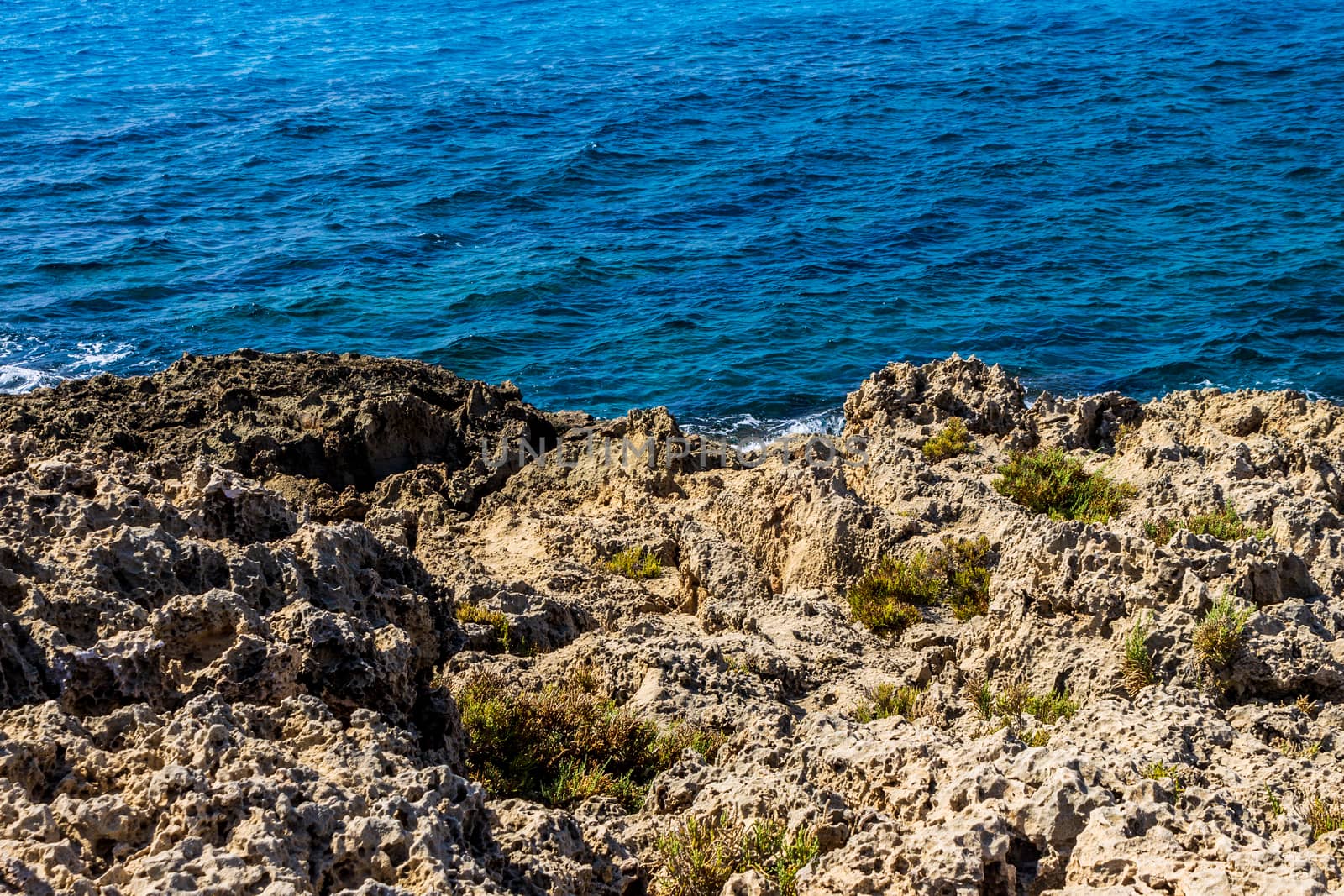 Mediterranean coast on a sunny day with rocks and blue waves.